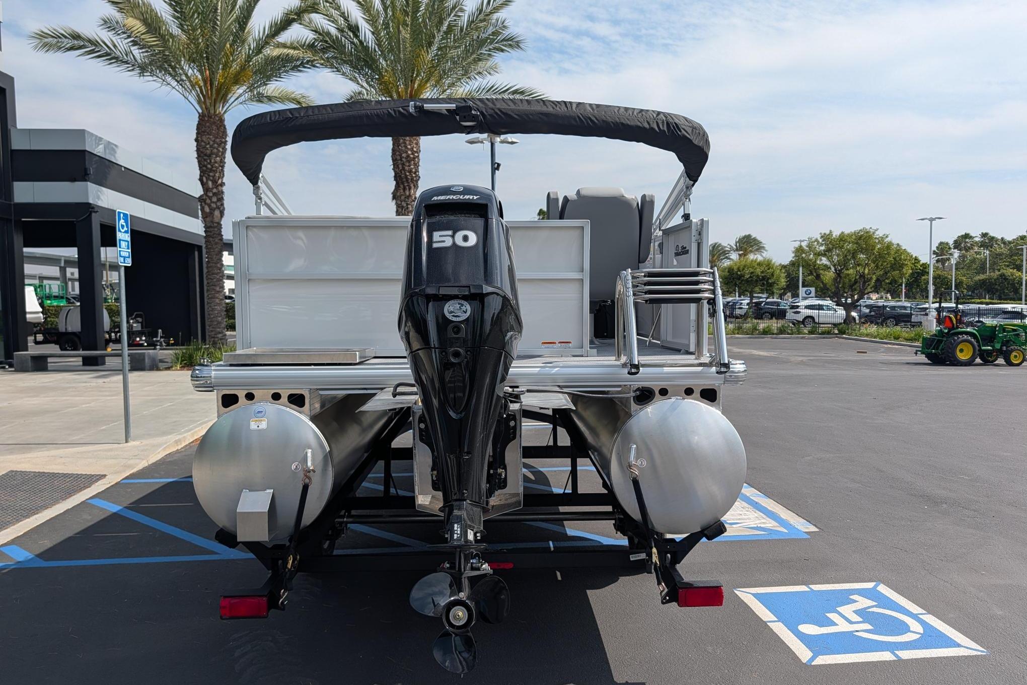 2026 Sun Tracker Party Barge 16 DLX pontoon boat with Mercury 50 engine in parking lot.