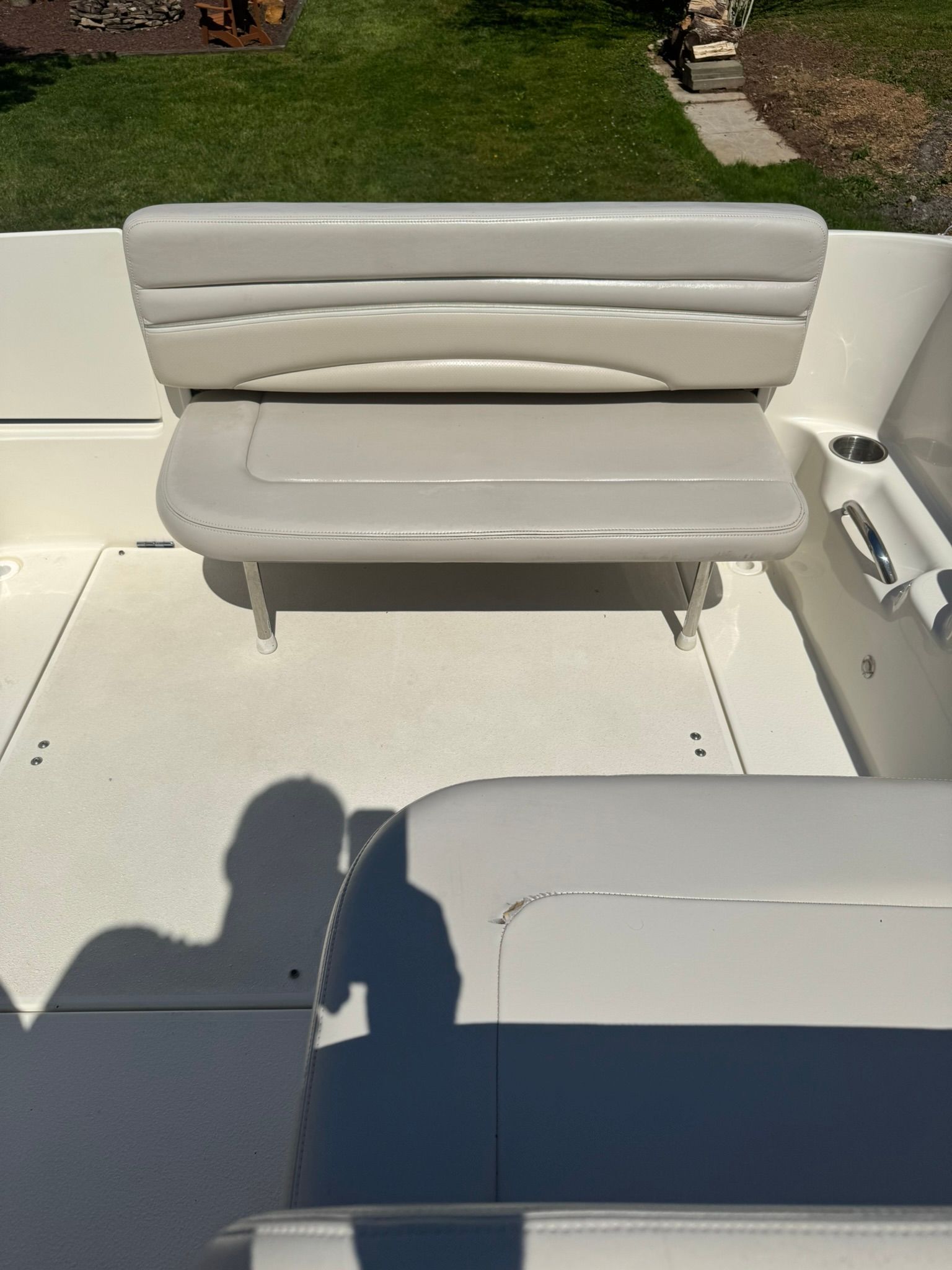A white boat with a cushioned bench seat and cup holders.