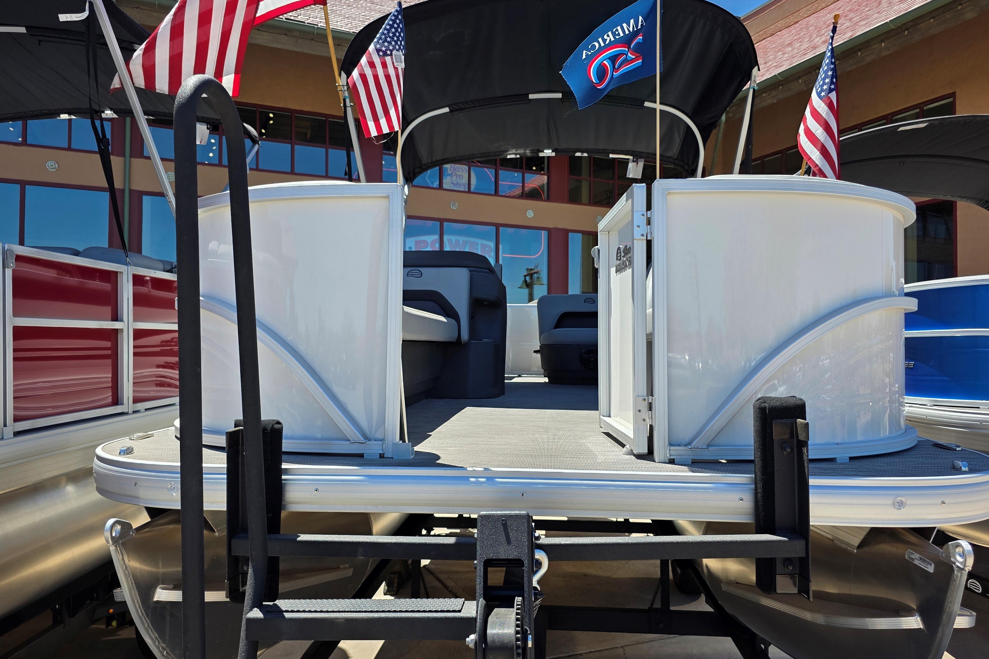2026 Sun Tracker Party Barge 18 DLX pontoon boat with American flags displayed.