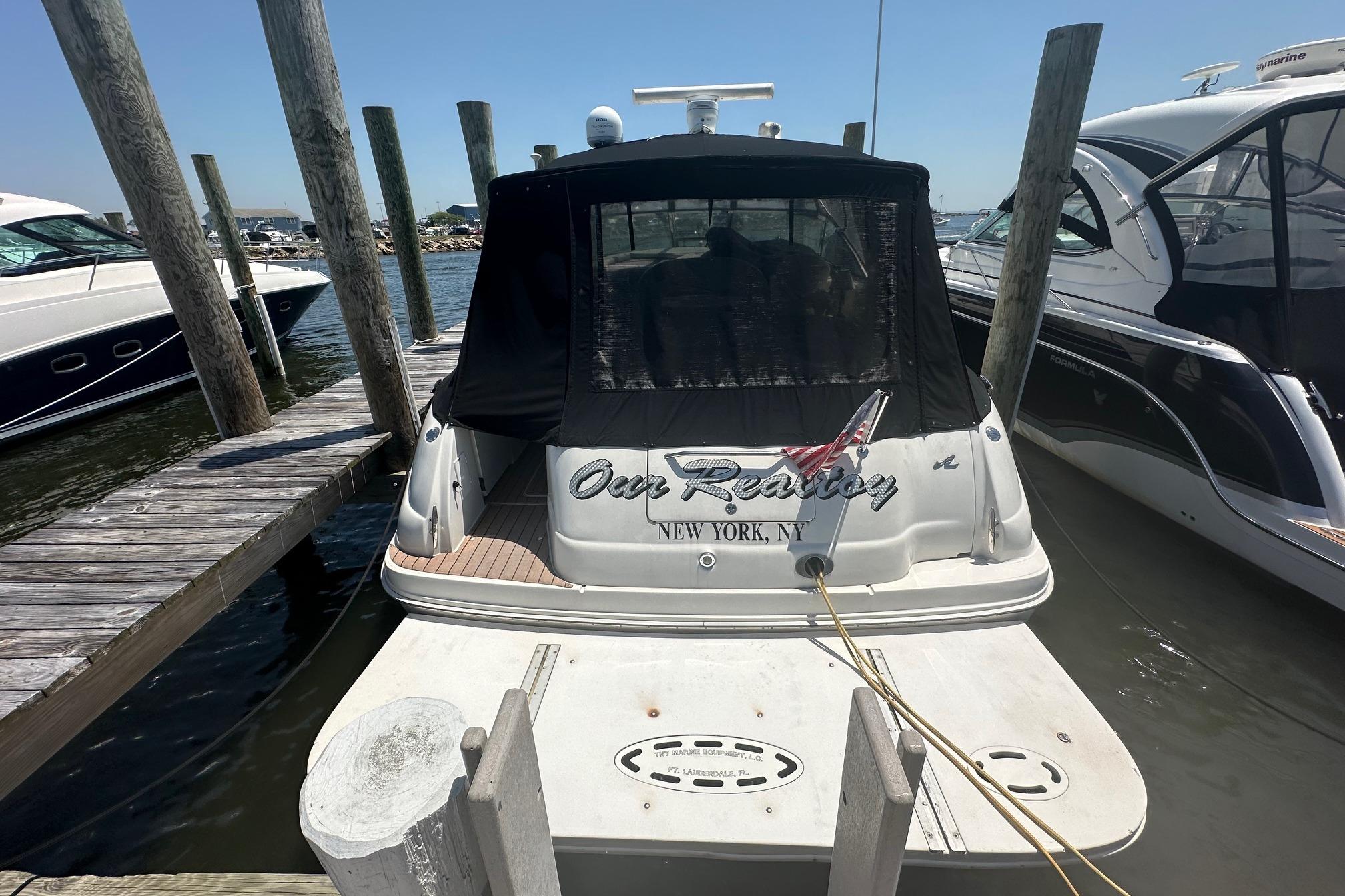 2001 Sea Ray 410 Sundancer docked at marina, rear view with black cover.