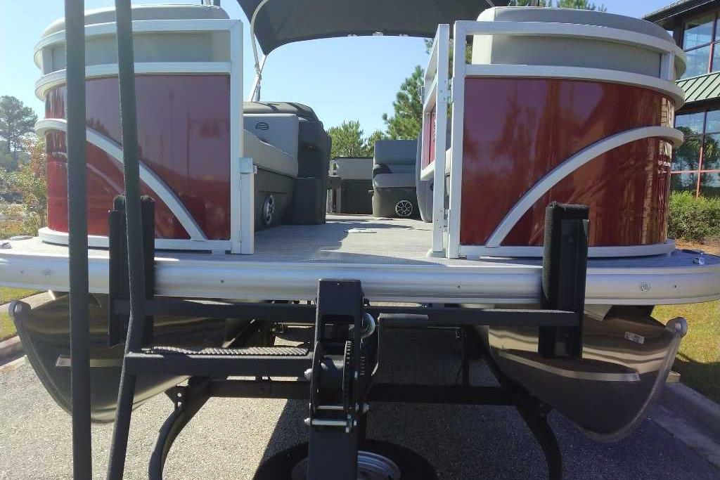 2026 Sun Tracker SportFish 22 DLX pontoon boat, red and white, parked on a trailer.