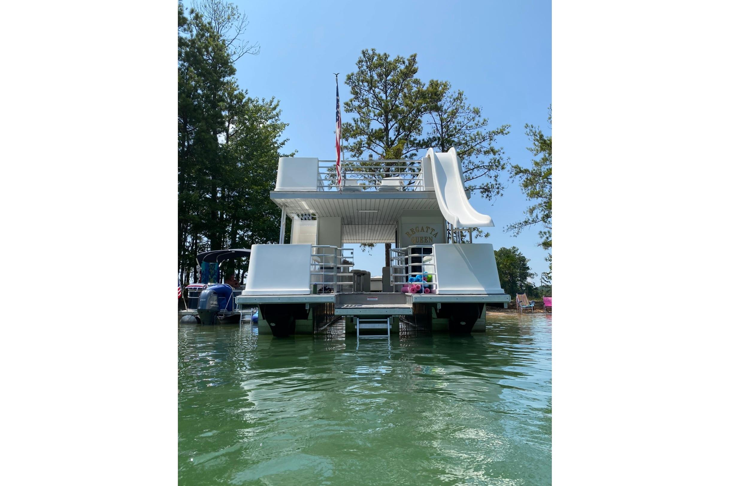 2008 Destination Yachts 45X14 houseboat with slide, docked on a serene lake.
