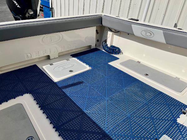 2023 Defiance Admiral 220 EX boat deck with blue matting and storage compartments.