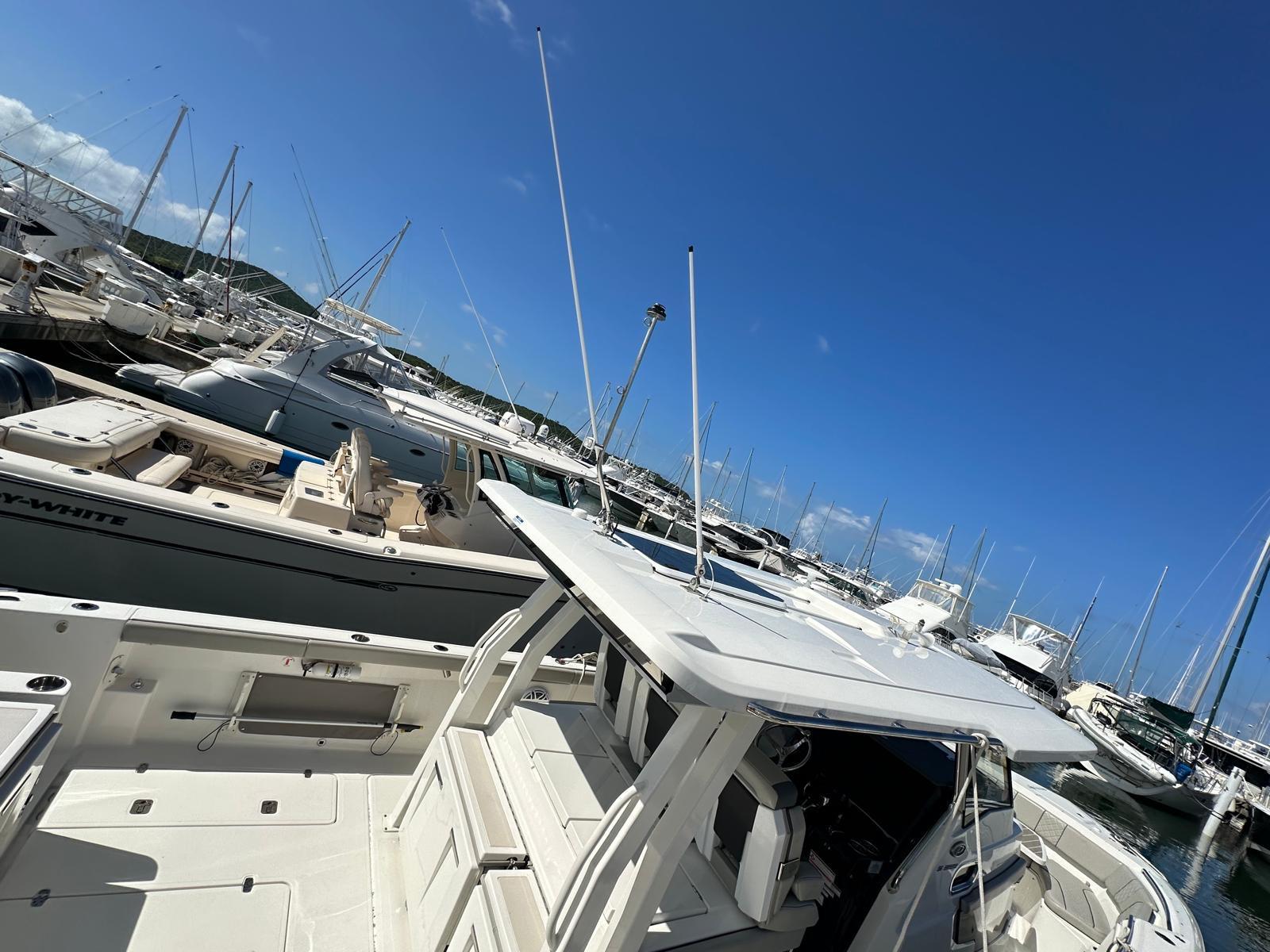 2023 Pursuit S 358 Sport boat docked in a marina under clear blue skies.