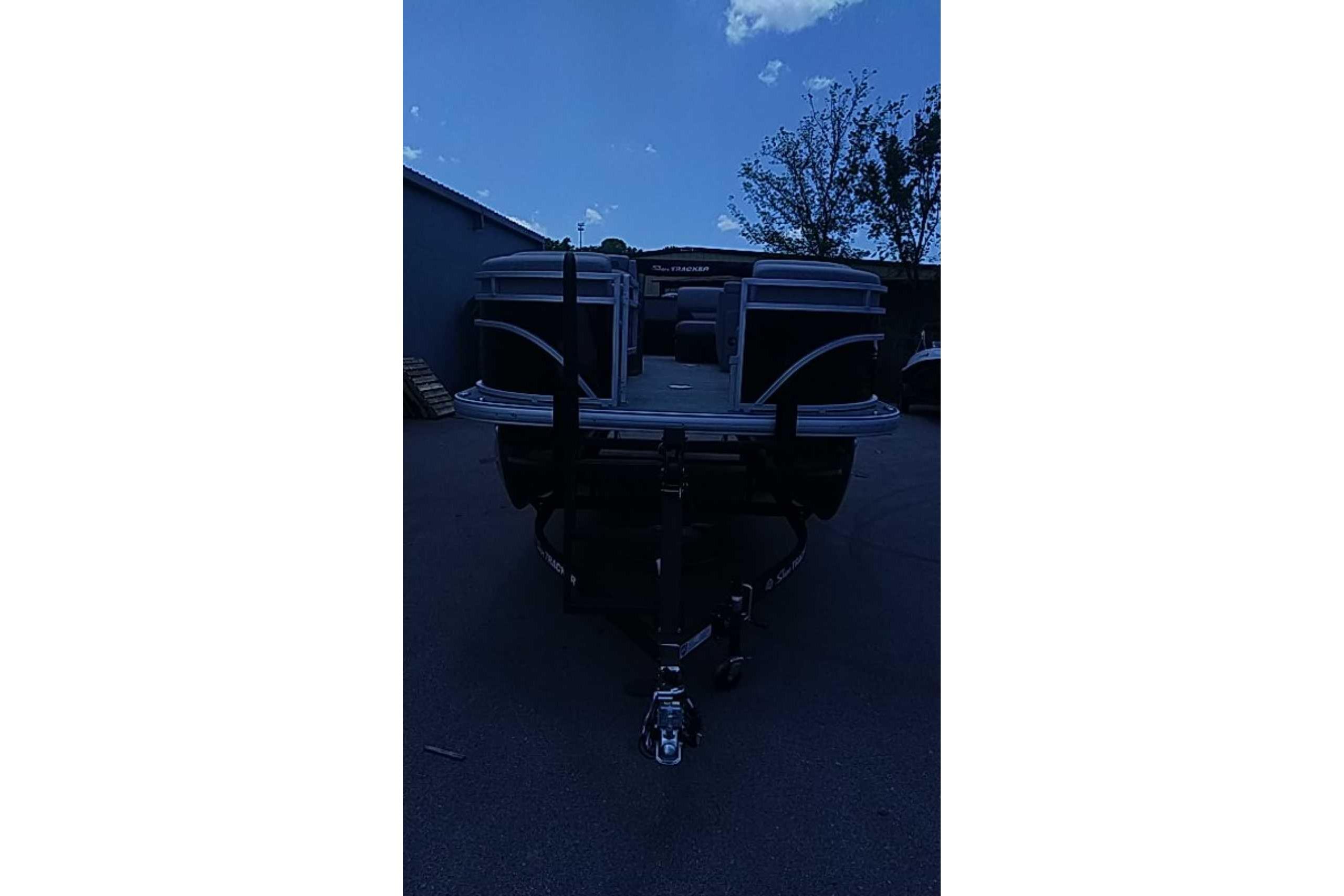 2026 Sun Tracker SportFish 22 DLX pontoon boat on trailer, parked outdoors.