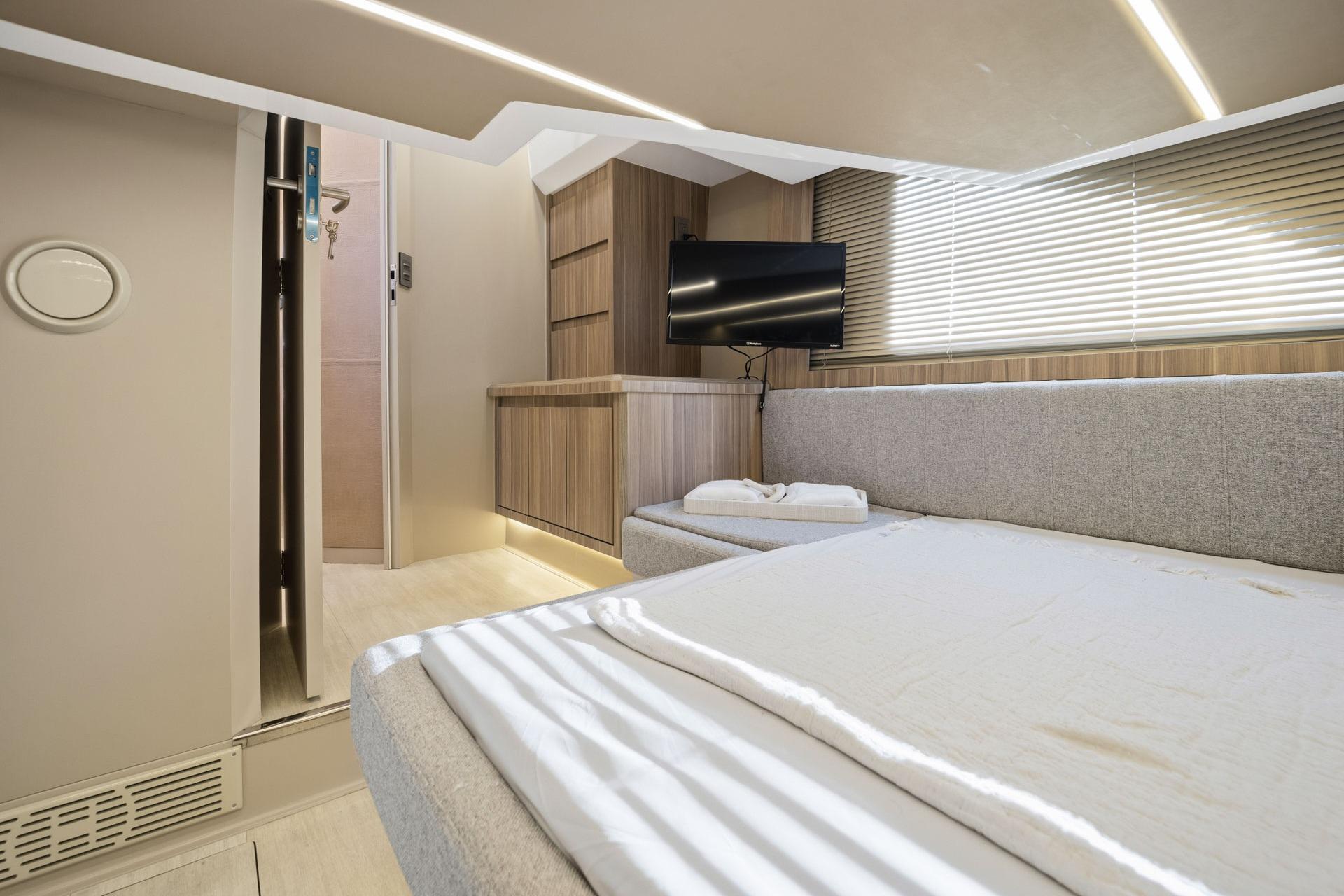 Modern interior of Hanover 447 yacht, featuring a cozy bed, TV, and sleek wooden accents, 2026 model.