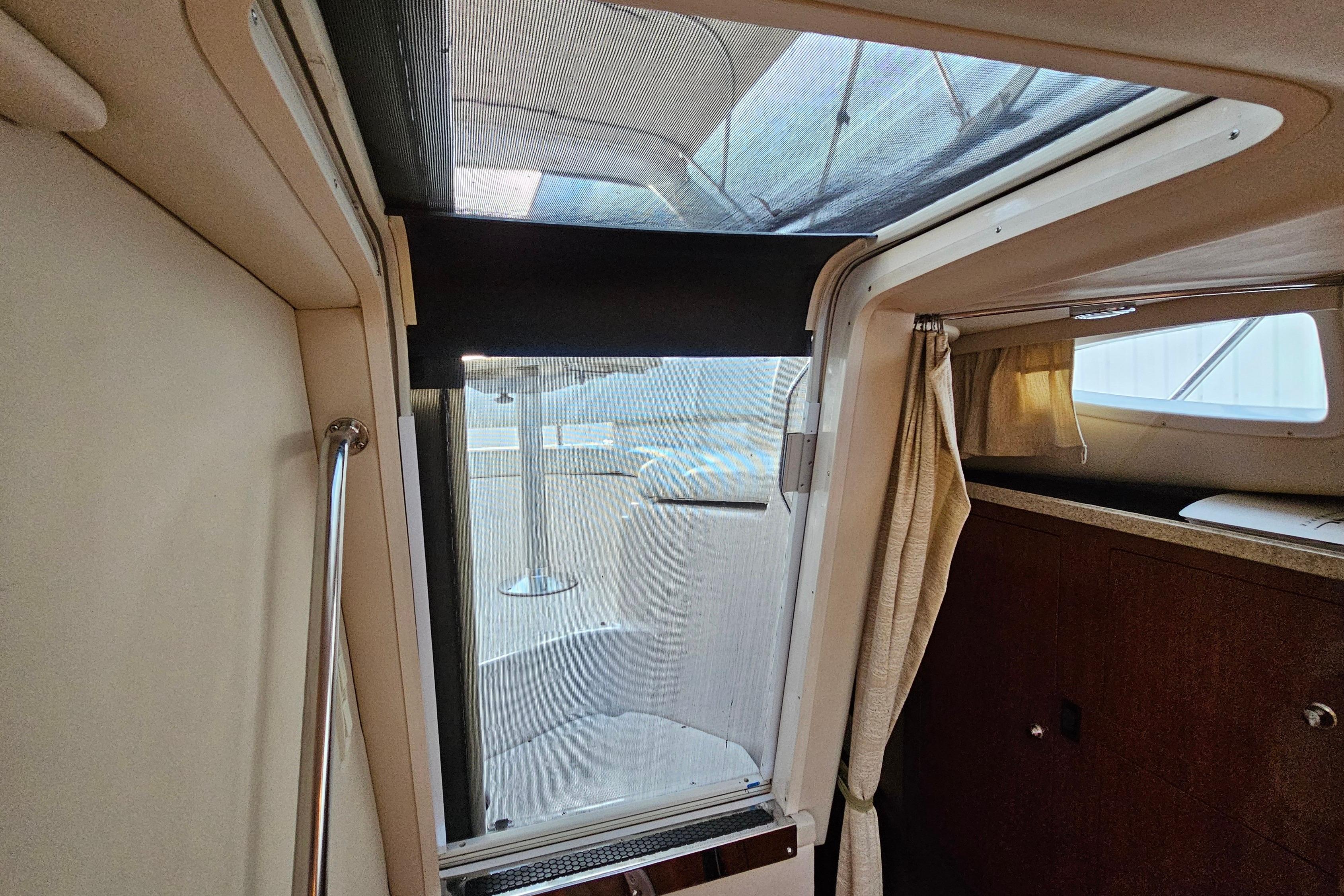 Interior view of a 2005 Regal 3060 Window Express boat cabin with curtains and seating.