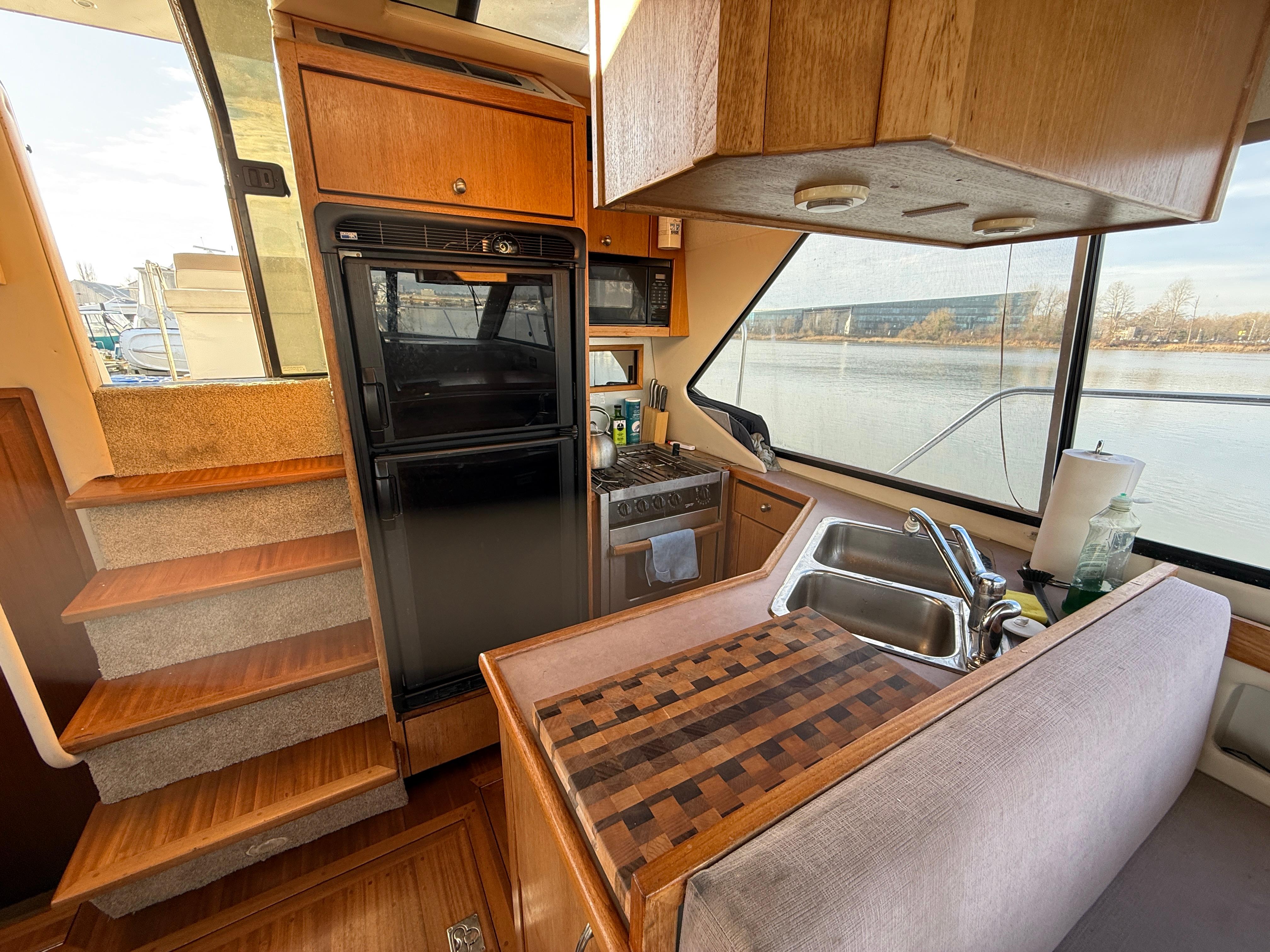 1998 Bayliner 4087 Aft Cabin Motoryacht kitchen with wood cabinetry and large windows.