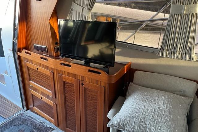 Interior of 1998 Storebro 430 Royal Cruiser with TV and wooden cabinetry.