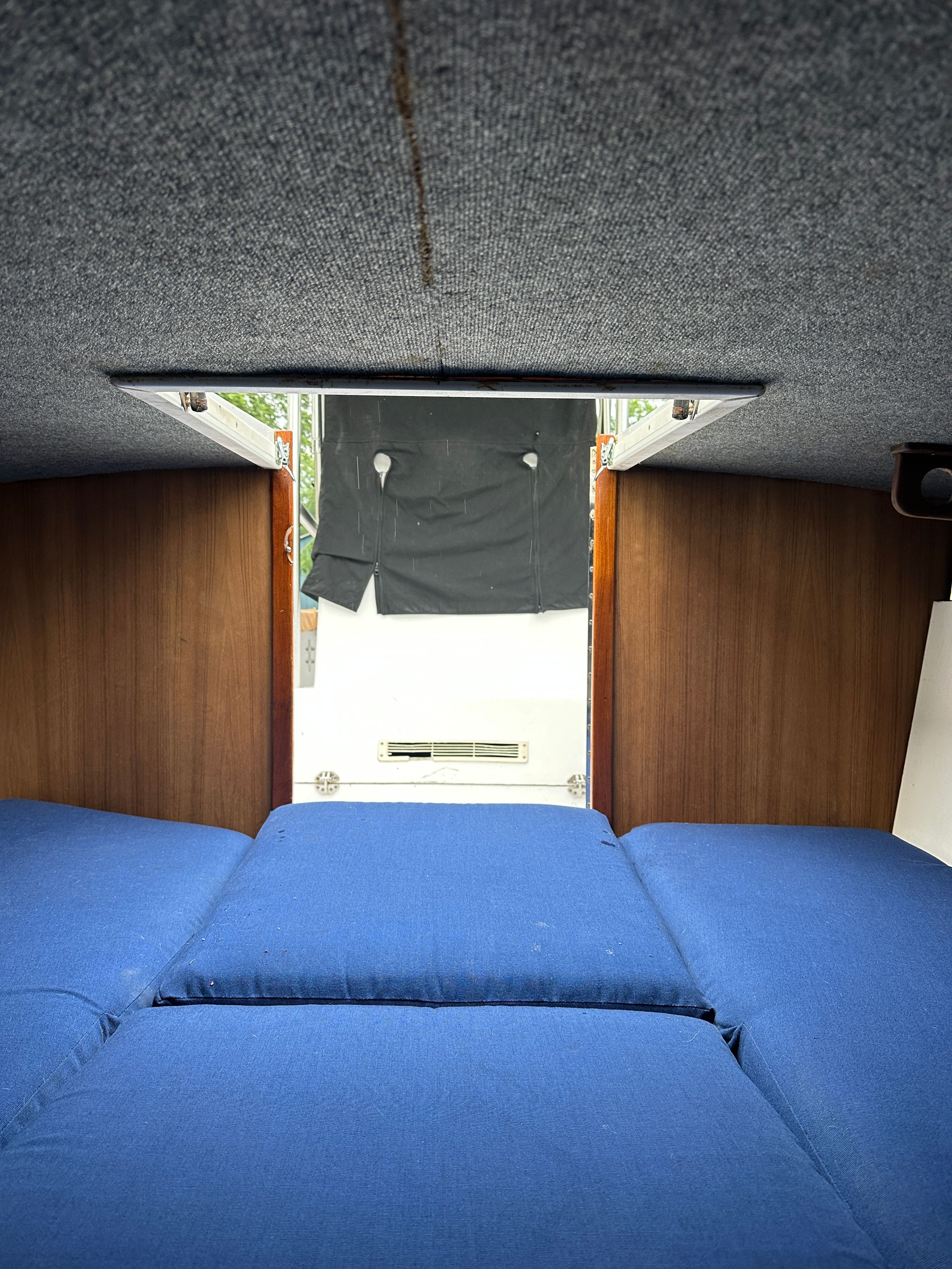 Interior of a 1976 Blackfin Fisherman with blue cushions and wooden walls.