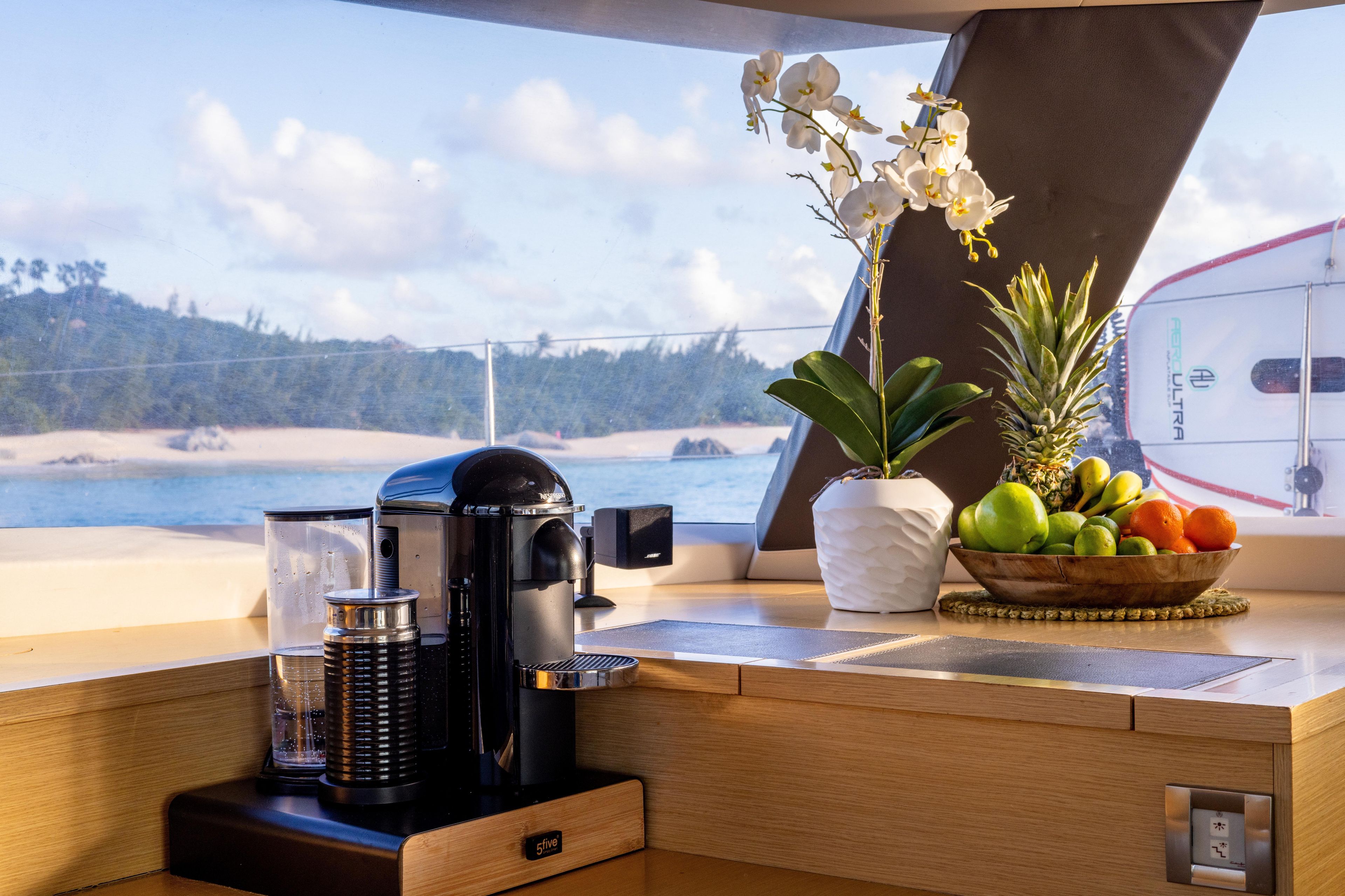 Luxurious 2017 Fountaine Pajot Victoria 67 yacht interior with coffee maker, fruit, and ocean view.
