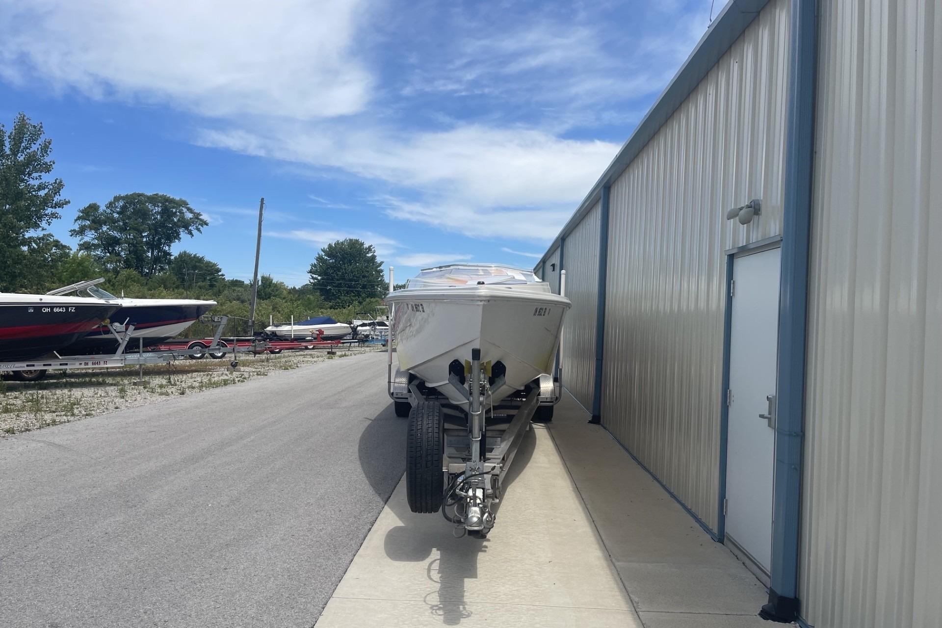 2006 Sonic 386 boat on trailer beside a metal building under a clear sky.