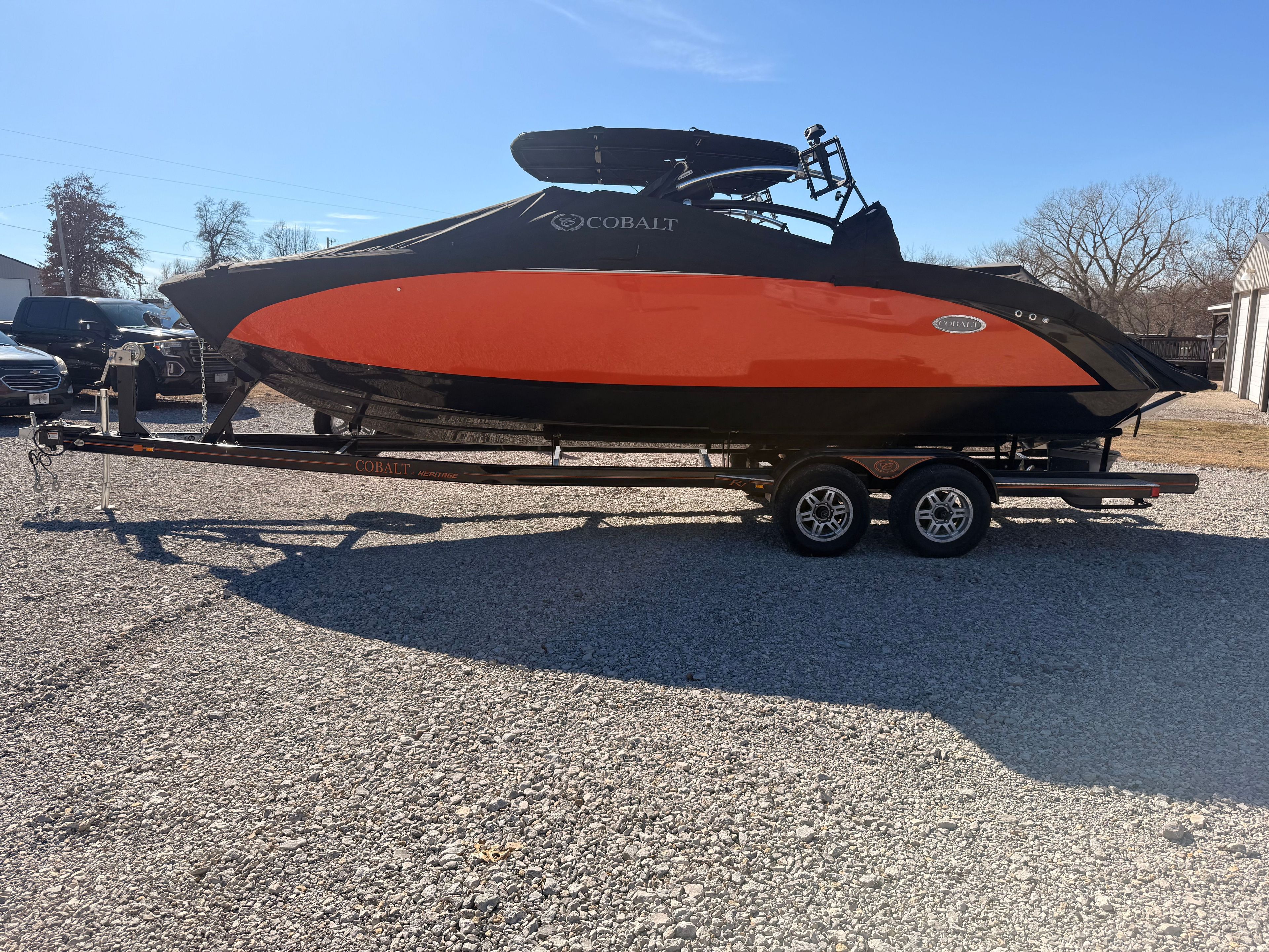 A 2019 Cobalt R7 Surf boat with a black and orange hull sits on a trailer.