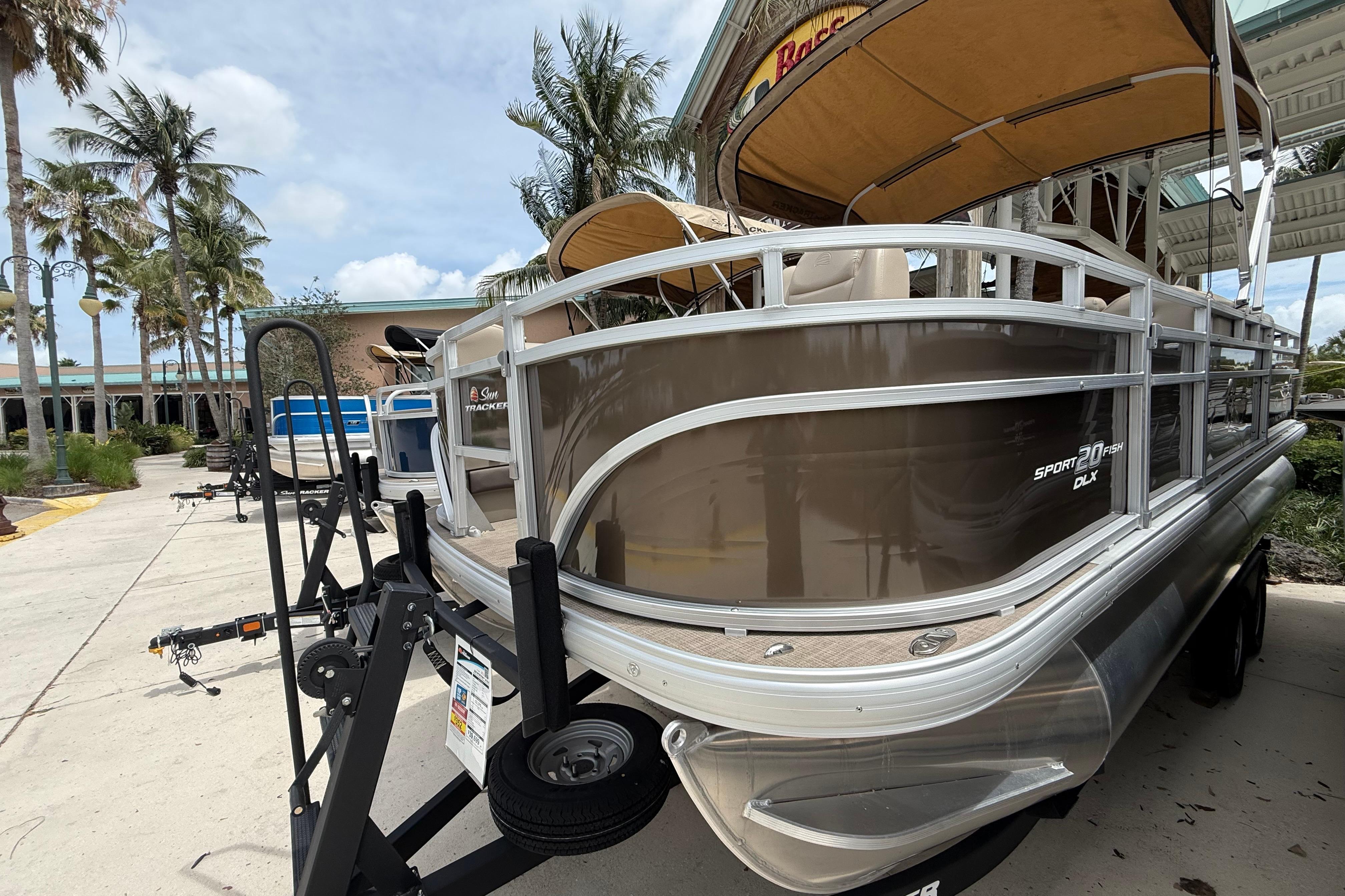 2025 Sun Tracker SportFish 20 DLX pontoon boat displayed outdoors with palm trees.