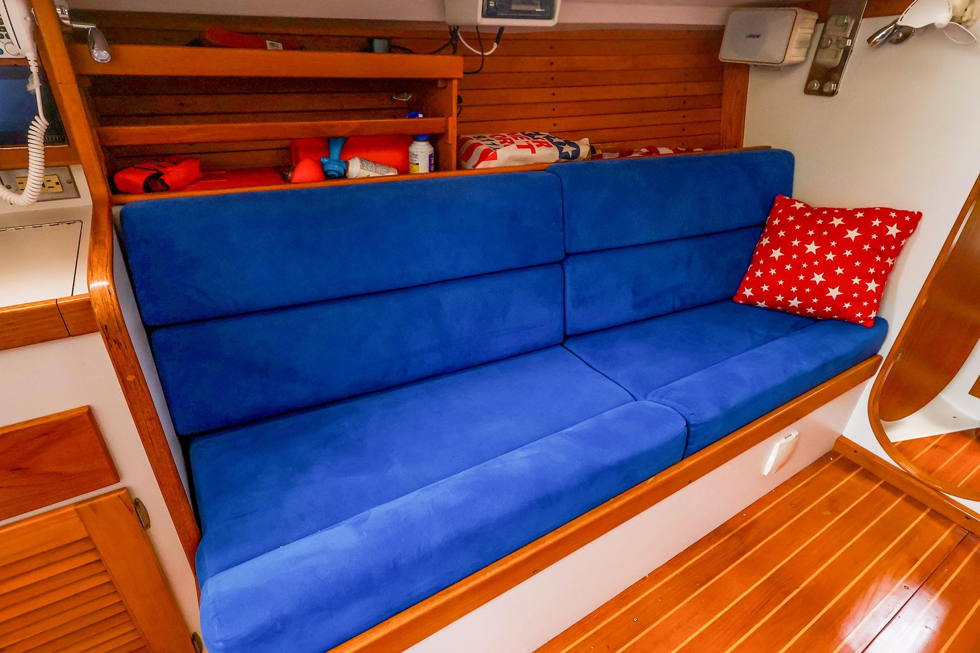 Interior of 2001 J Boats J/32 with blue seating and star-patterned pillow.