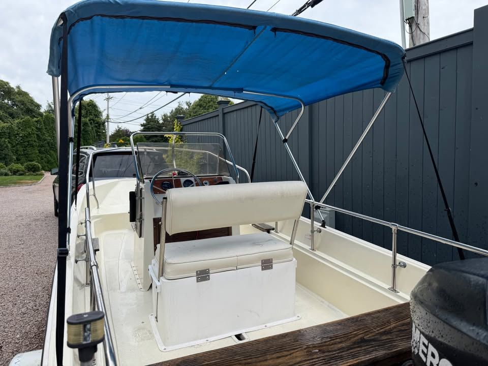 A 1976 Boston Whaler 17 Montauk with a blue Bimini top and white interior.