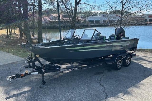 2025 Ranger VX1988 WT boat on trailer near lake, surrounded by trees and buildings.