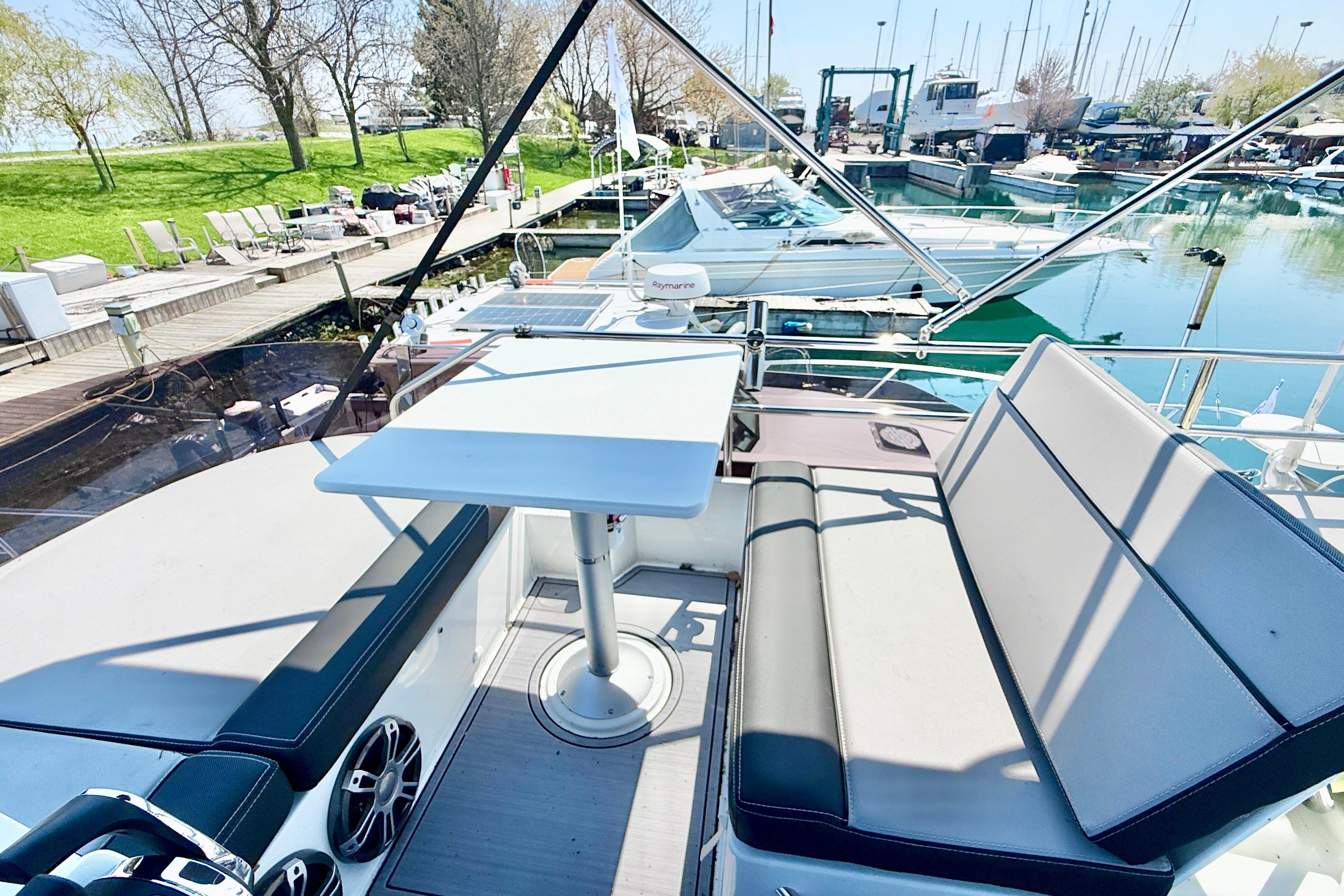 Flybridge view of 2022 Jeanneau NC 1095 Fly, featuring seating and table at marina.