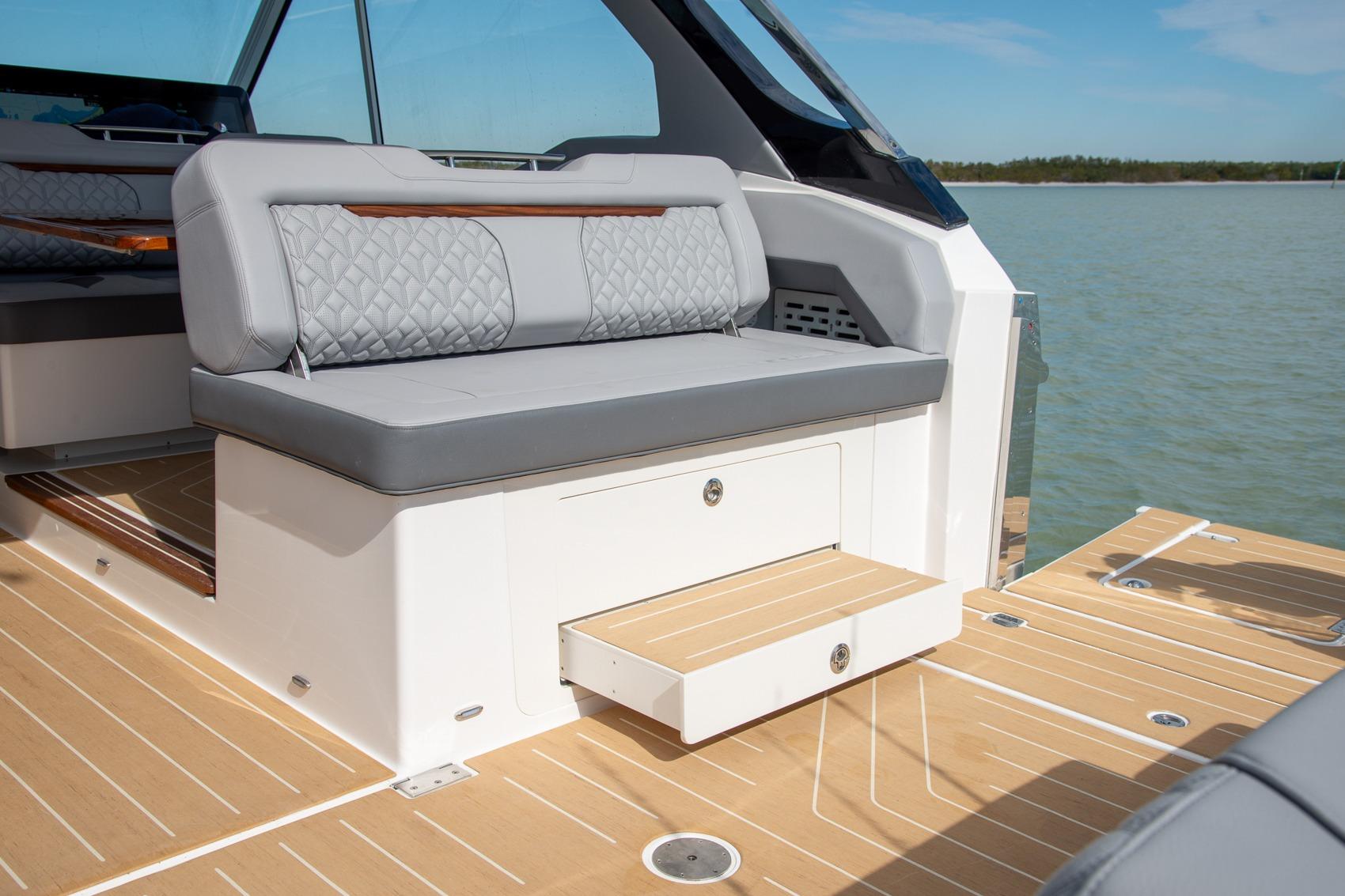 2026 Regal LX43 boat interior with gray seating and wooden deck, on a sunny day.