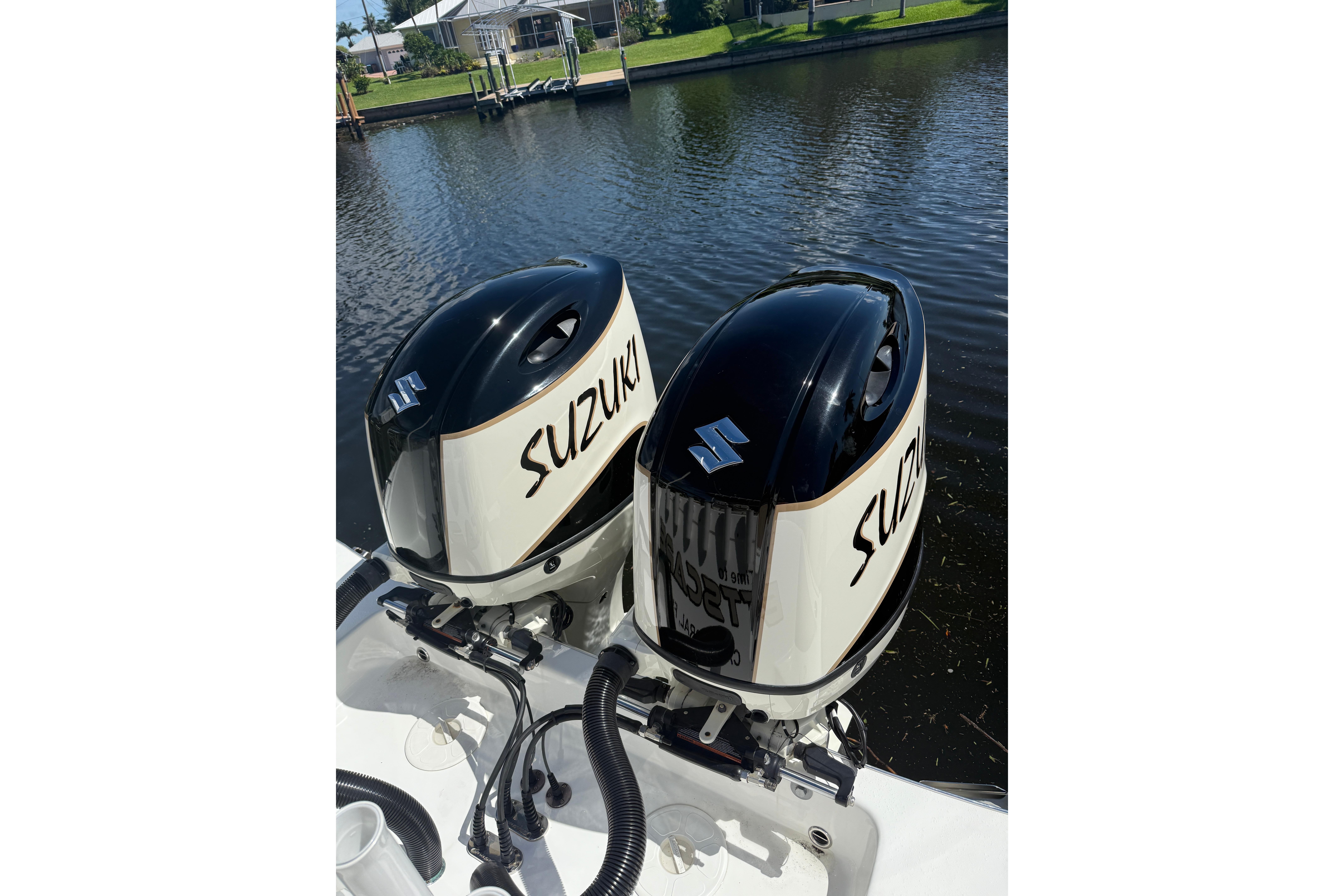 Twin Suzuki outboard engines on a 2019 Cape Horn 27XS boat by a canal.
