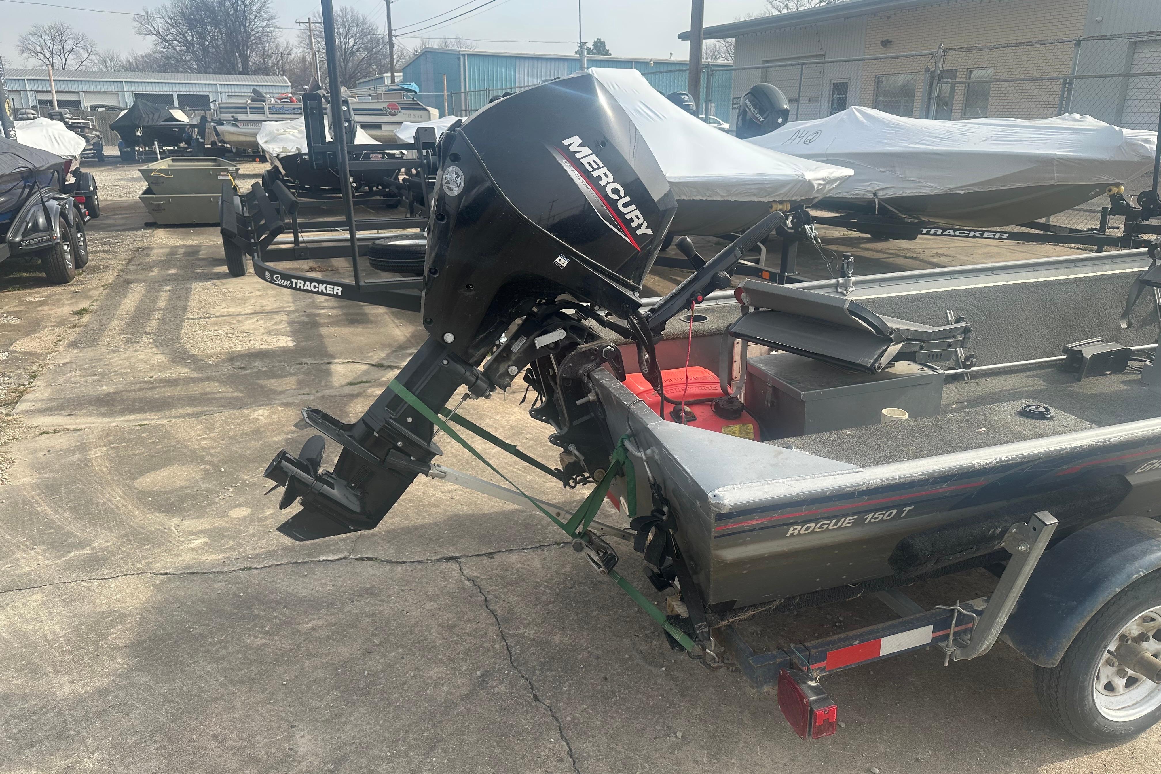 1991 Grumman Rogue 150 T boat with Mercury outboard motor in a storage yard.