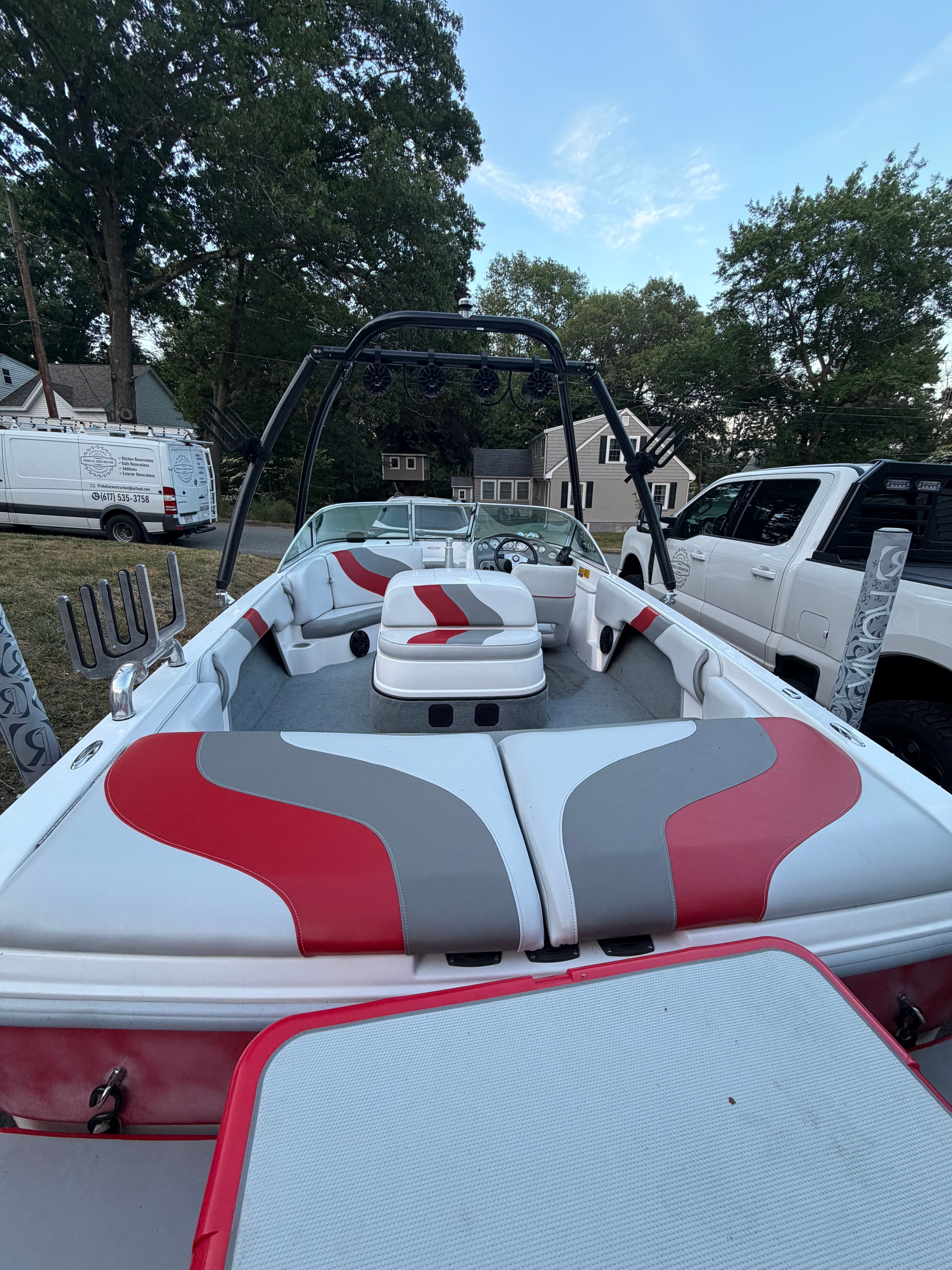 A 2002 Moomba Outback boat with red and gray seats, parked on a lawn.