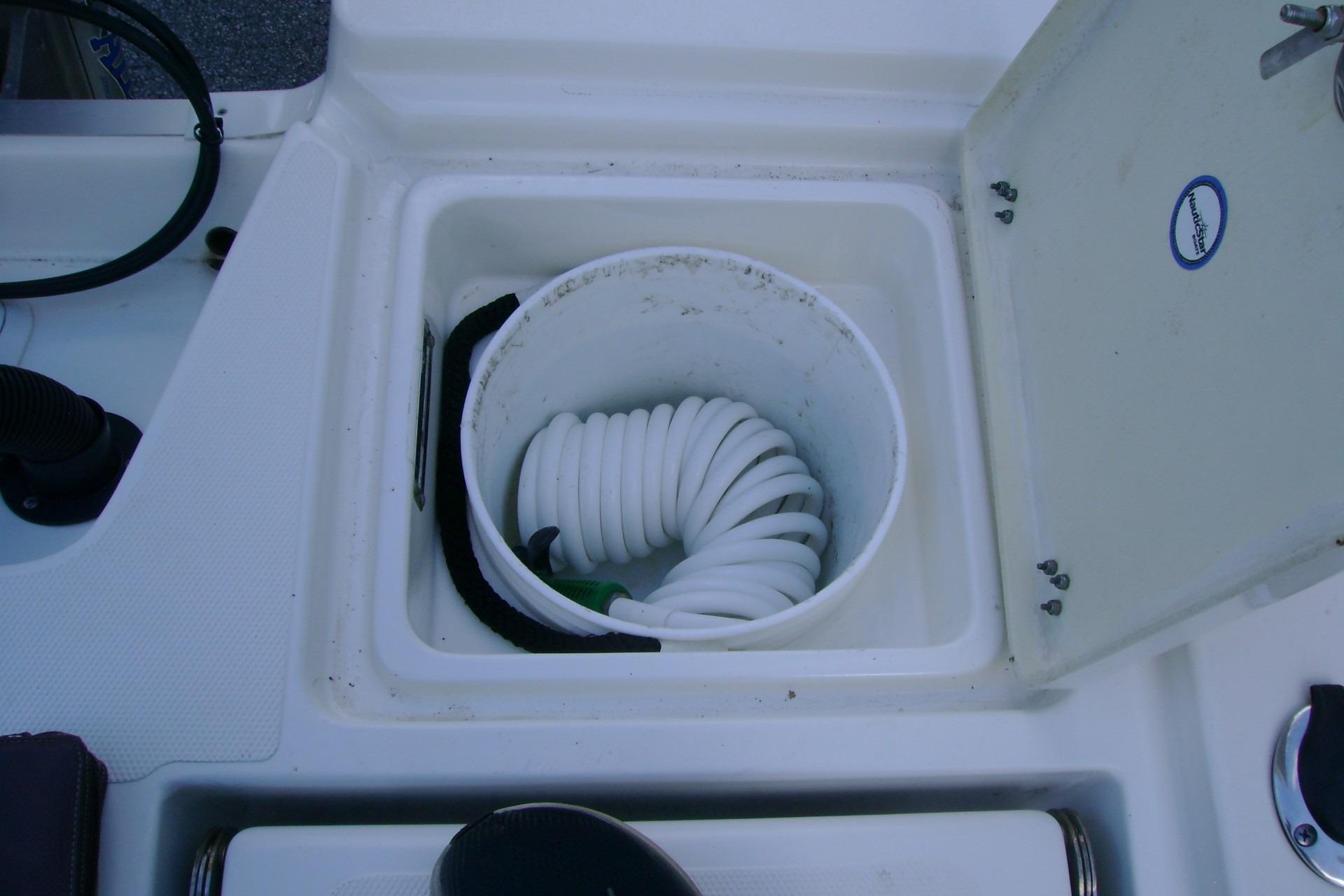 Storage compartment with coiled hose on 2022 NauticStar 227 XTS boat.