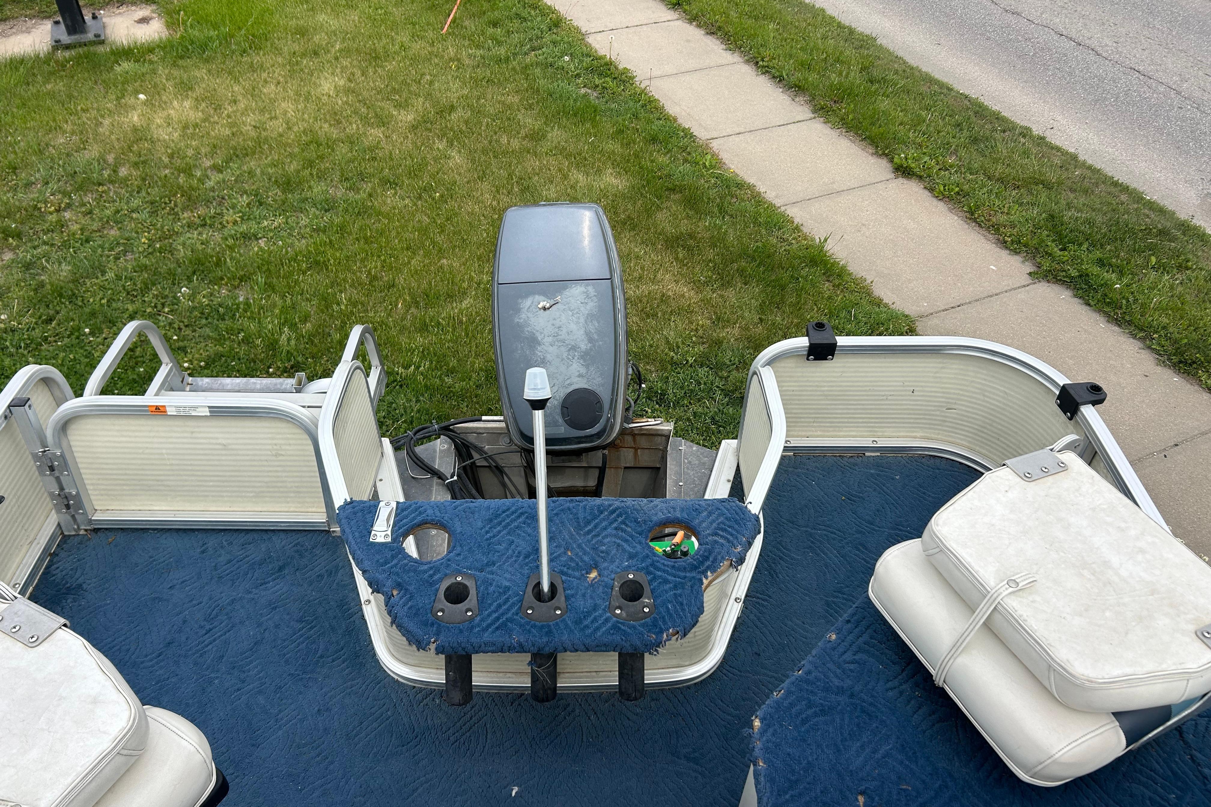 Pontoon boat deck with blue carpet, featuring seating and motor, Lowe Trinidad 200, 2002 model.