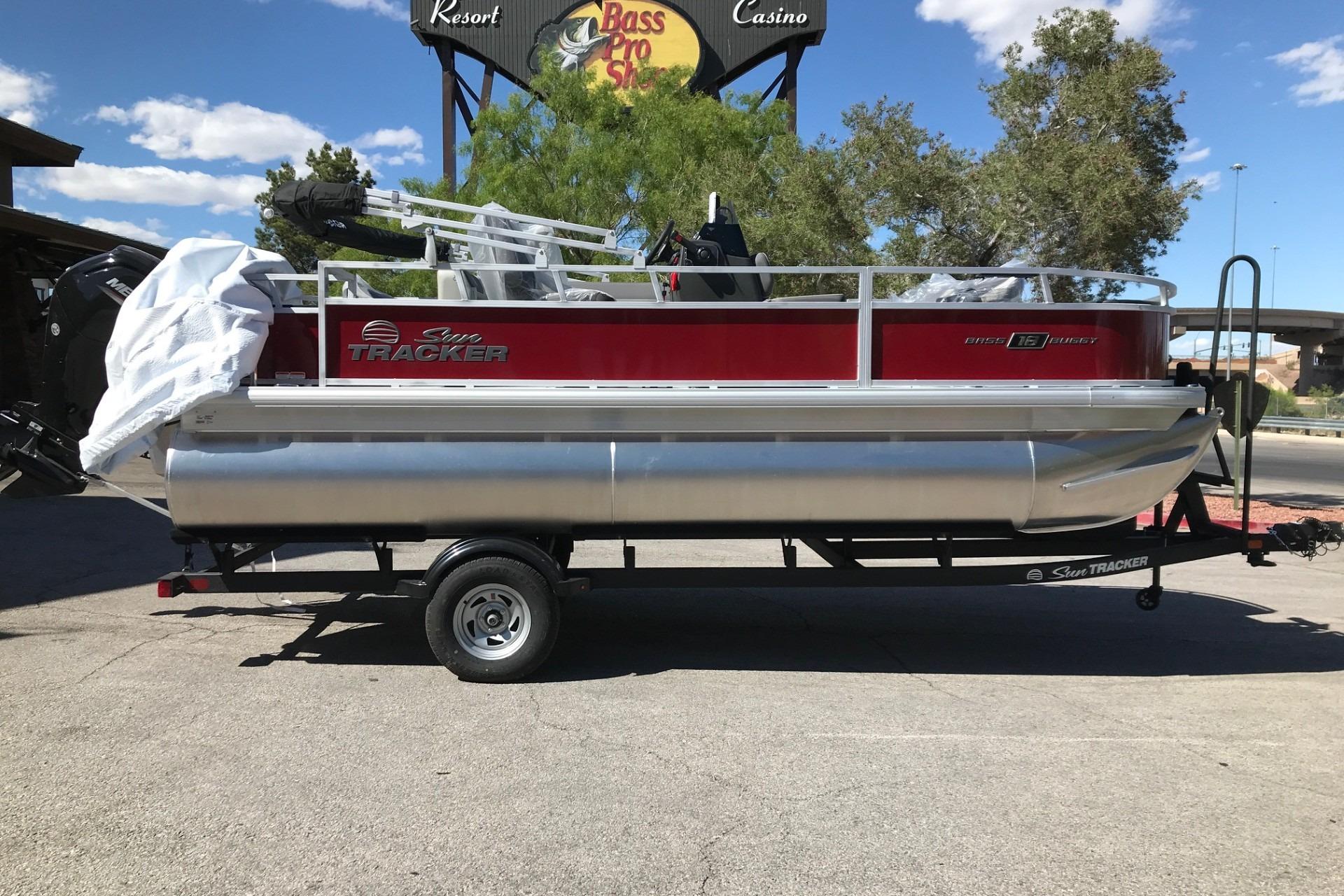 2026 Sun Tracker Bass Buggy 18 DLX pontoon boat on trailer, parked outdoors.