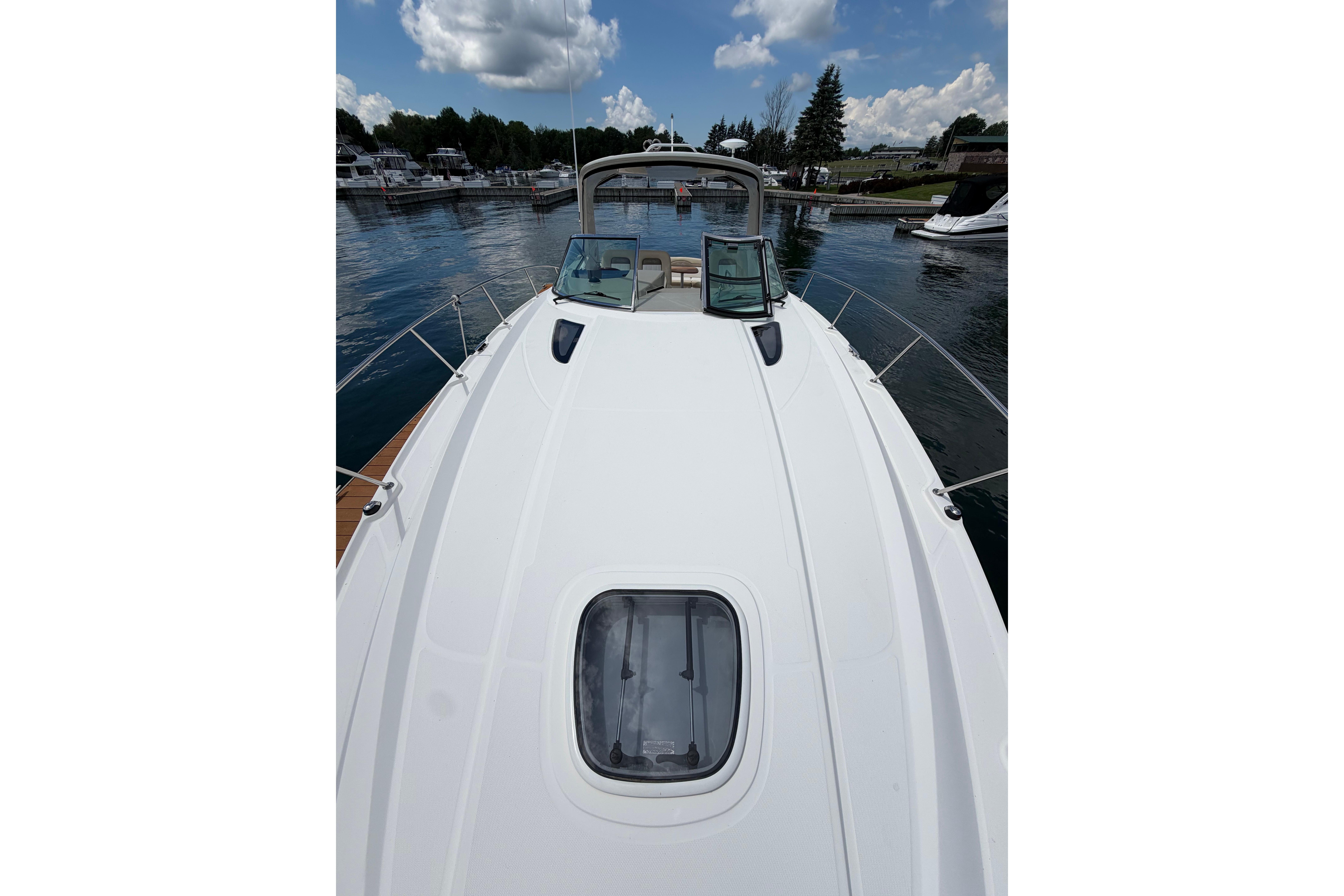 2012 Sea Ray Sundancer 370 yacht docked, showcasing sleek deck design under a partly cloudy sky.