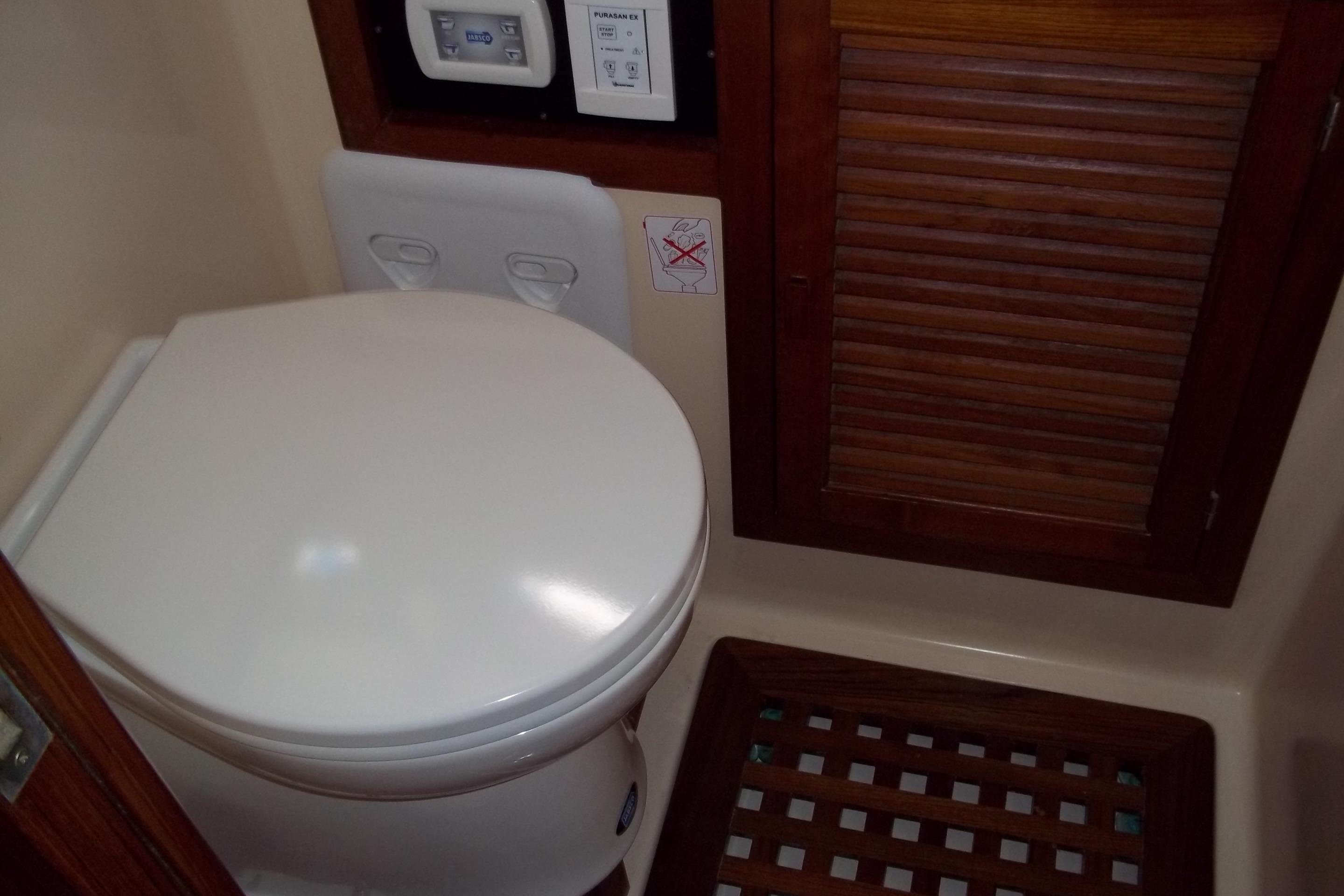 1984 Slocum 43 yacht bathroom with toilet and wooden cabinet.
