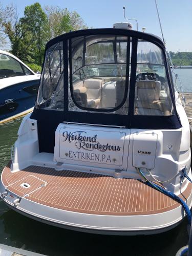 A 2008 Four Winns V338 docked. It features a blue cover and wooden deck.