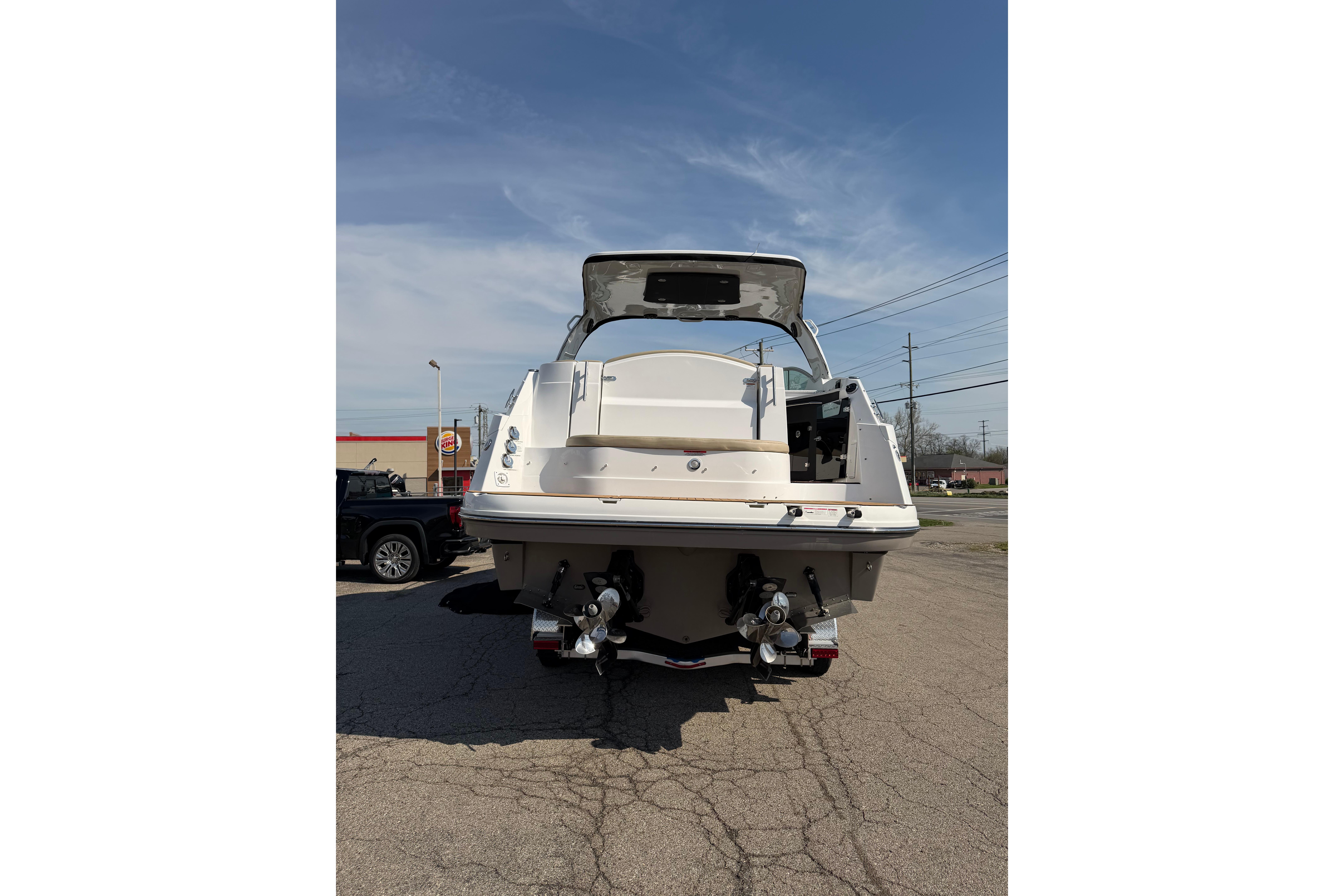 2019 Rinker EX 320 boat rear view in parking lot under clear sky.
