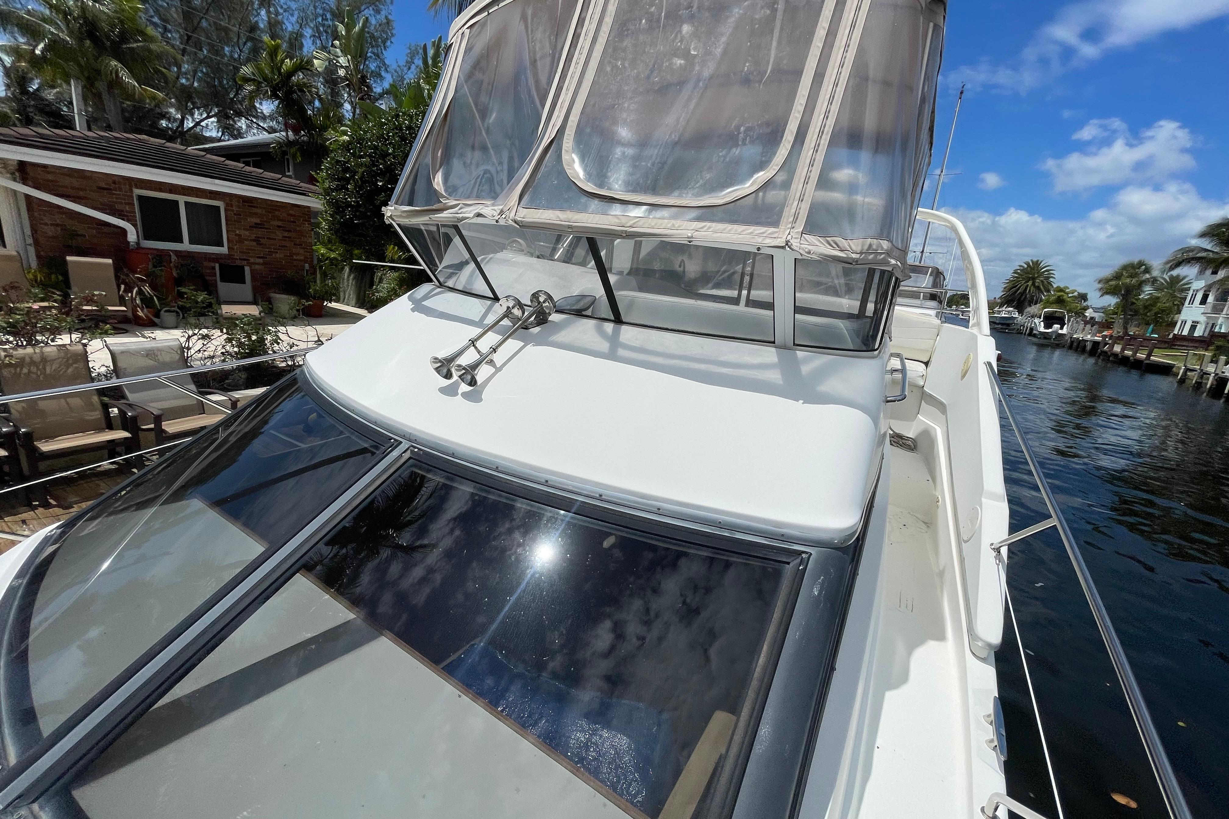 2002 Silverton 330 Sport Bridge yacht docked by a canal under a clear blue sky.