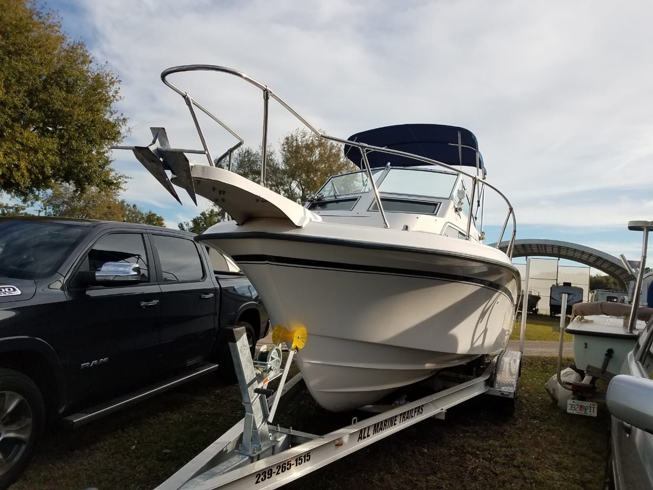 A 1995 Grady-White Explorer 24 on a trailer, parked beside a black vehicle.