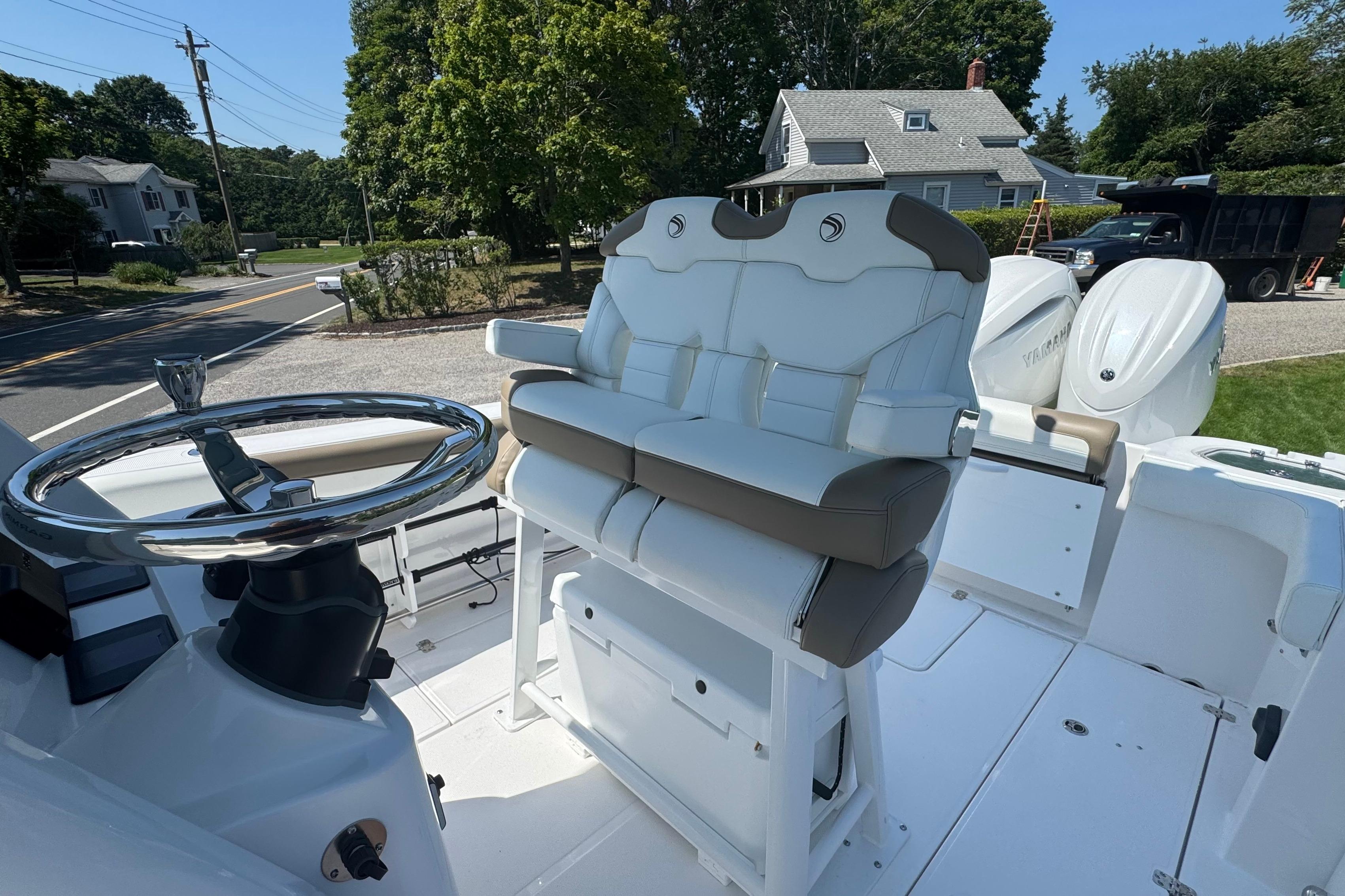 2026 Edgewater 250CC boat interior with dual seats and steering wheel, parked outdoors.