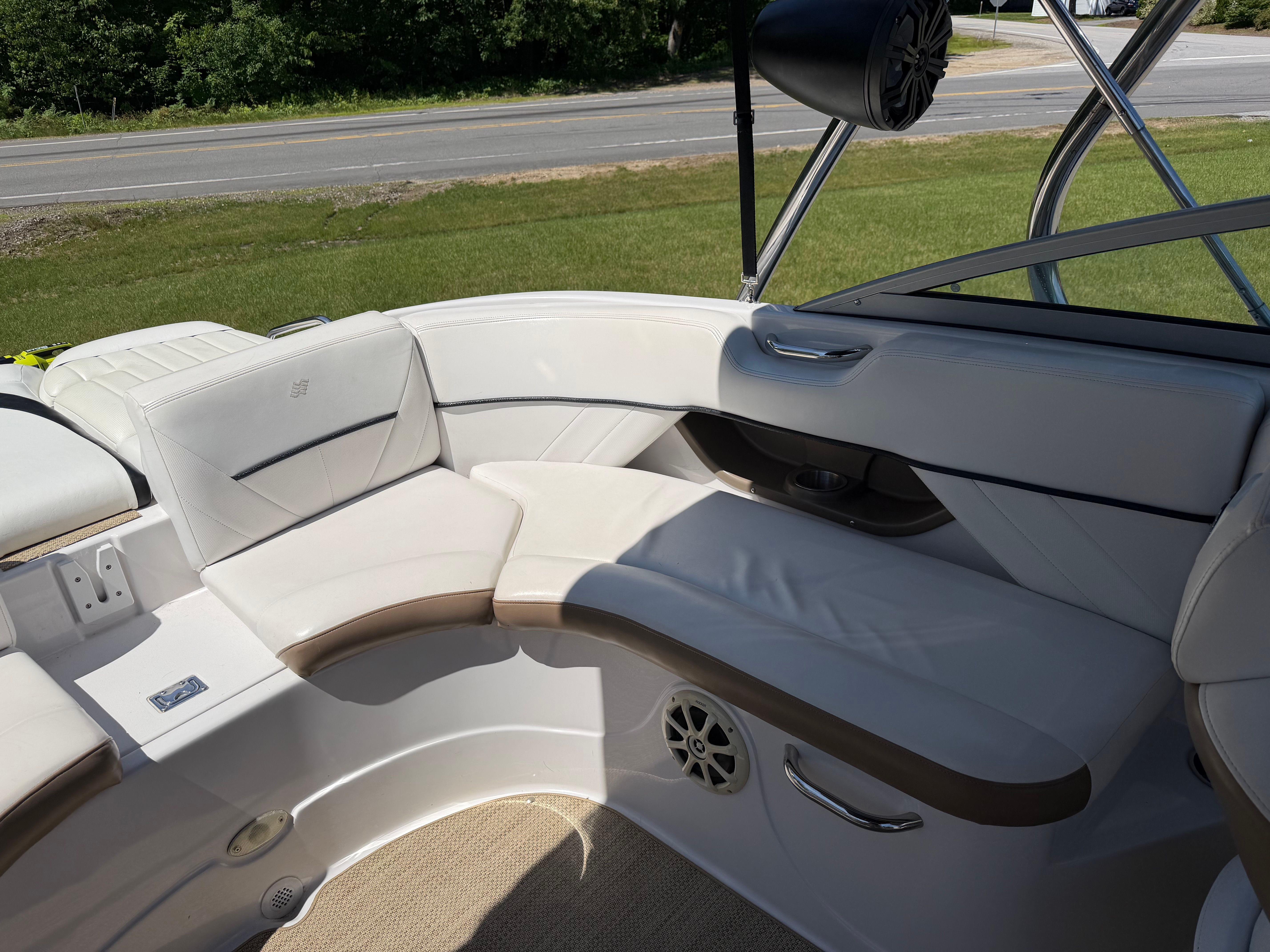Interior view of a boat with white upholstery and speakers.