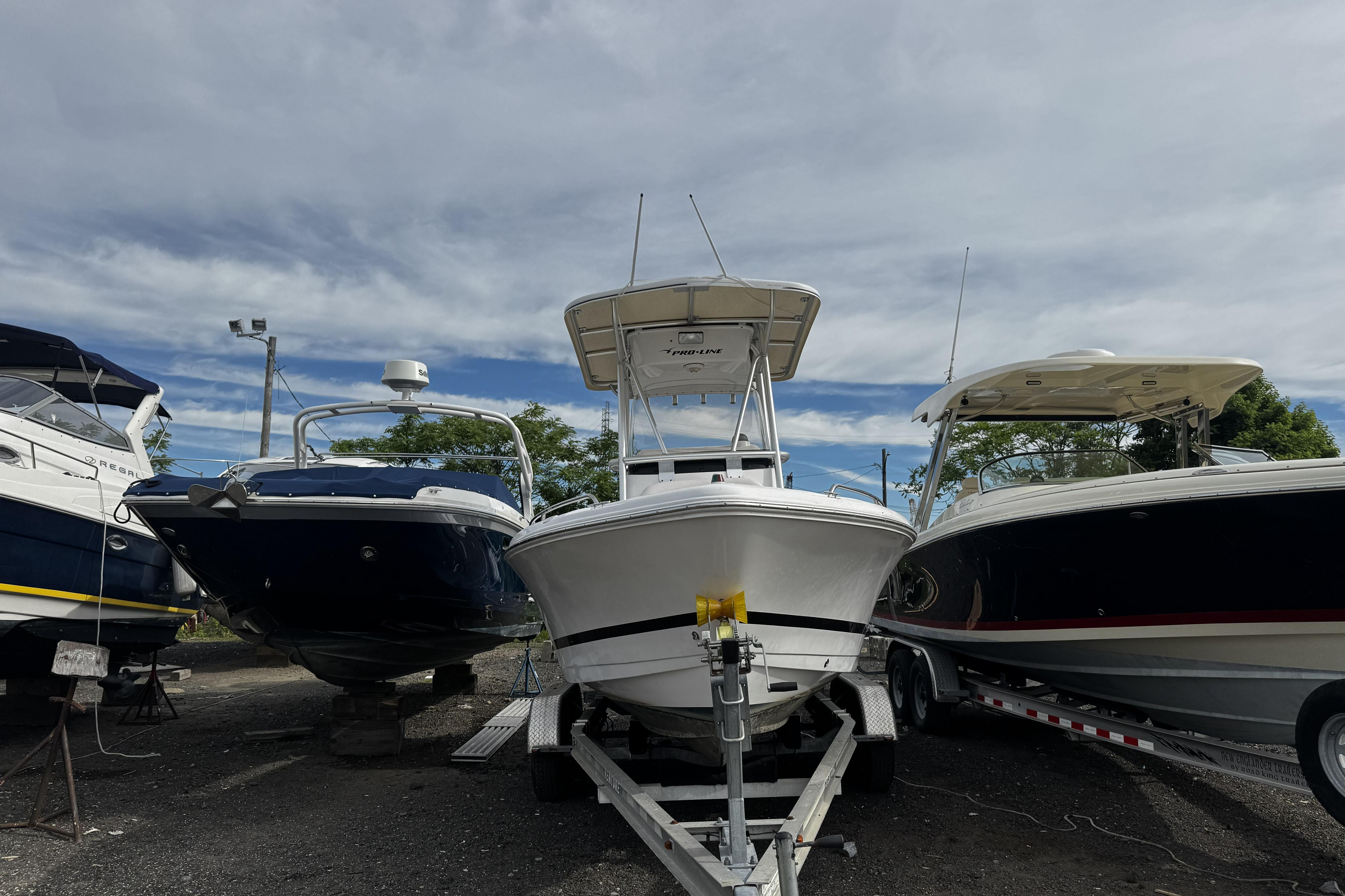2008 PROLINE 20 Sport boat on trailer, flanked by two other boats, under cloudy sky.