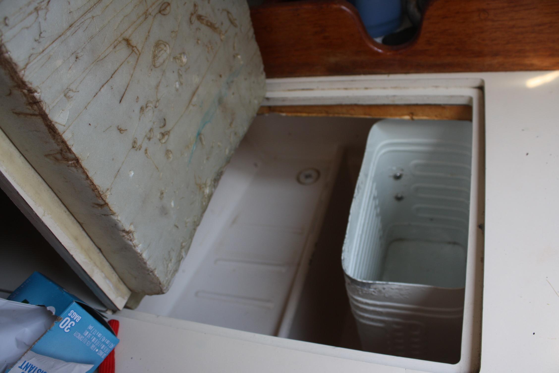 Open storage compartment on 1981 S2 9.2A sailboat with visible container inside.