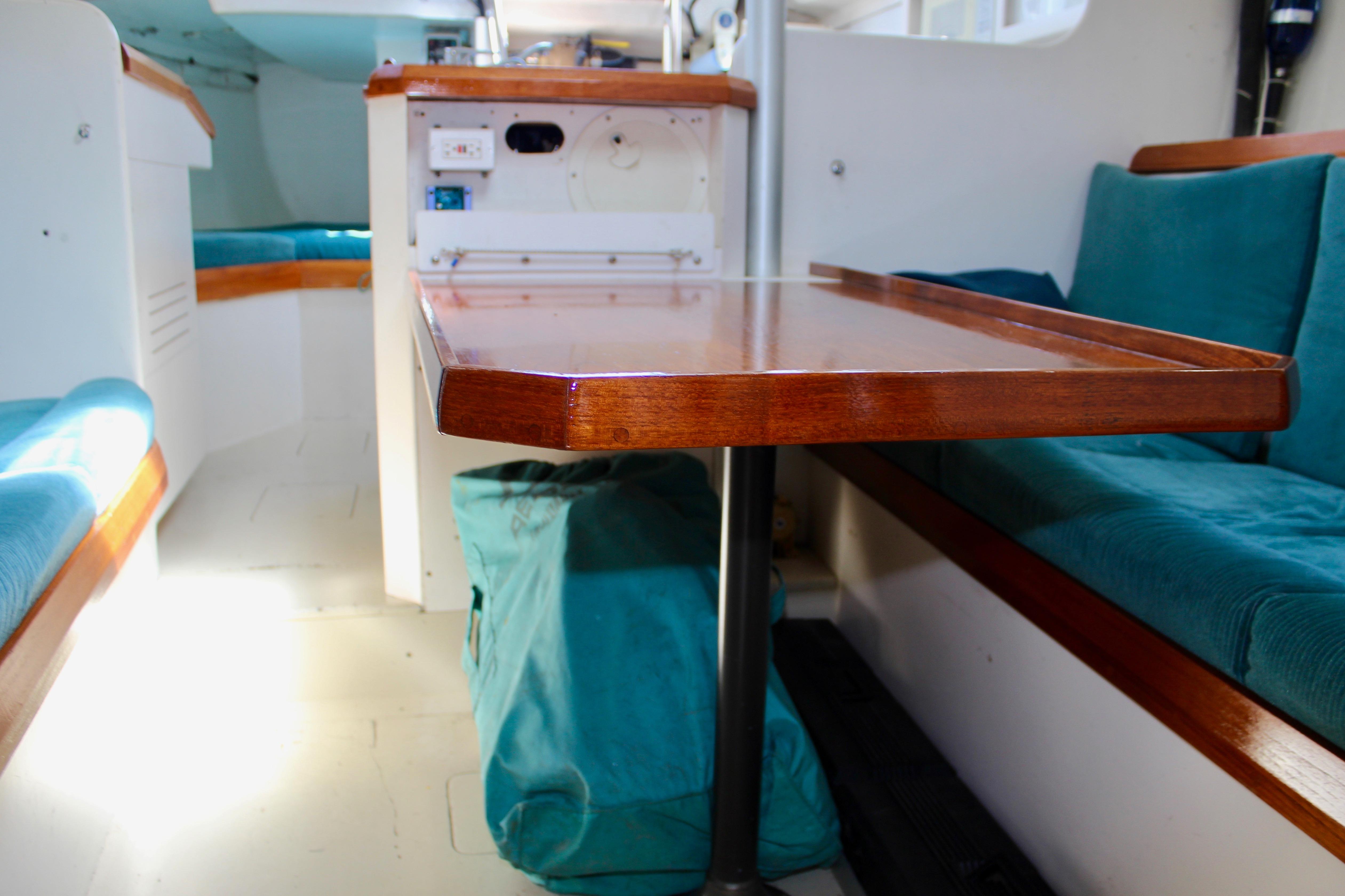 Interior of a 1993 Freya 39 sailboat with wooden table and teal seating.