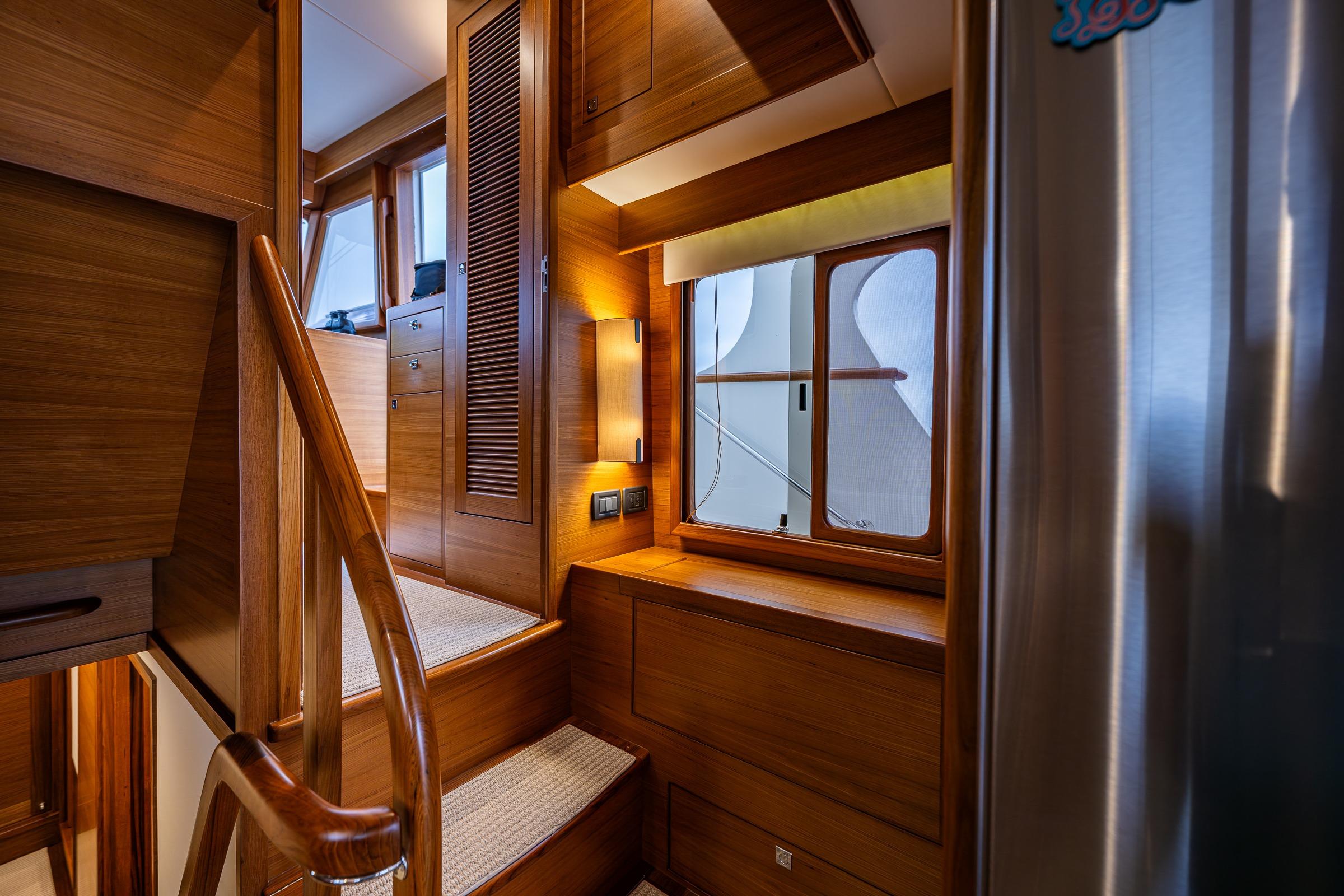 Luxurious wooden interior of 2026 Fleming 55 Pilothouse yacht with stairs and window.