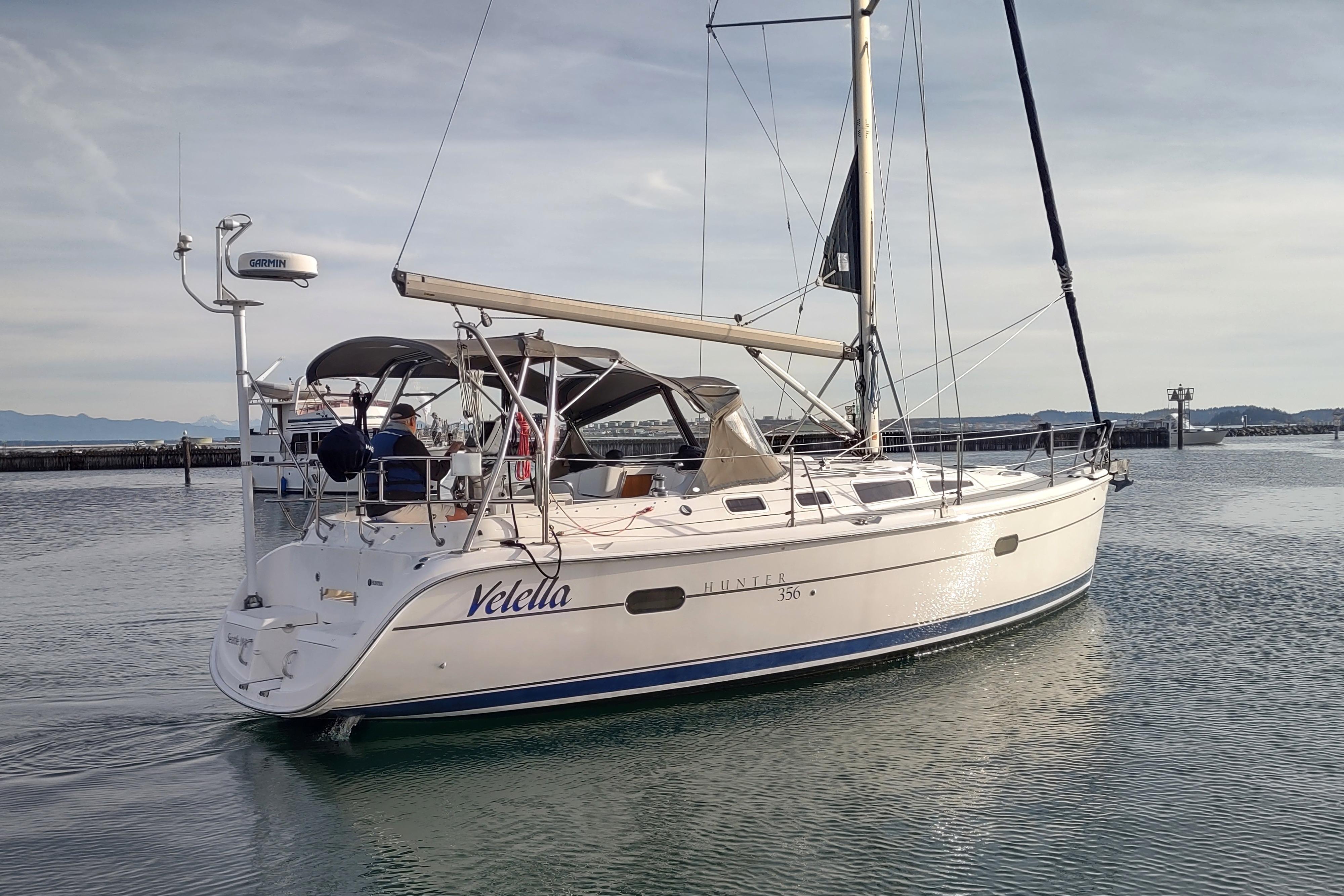 2003 Hunter 356 sailboat named Velella on calm water near a marina.