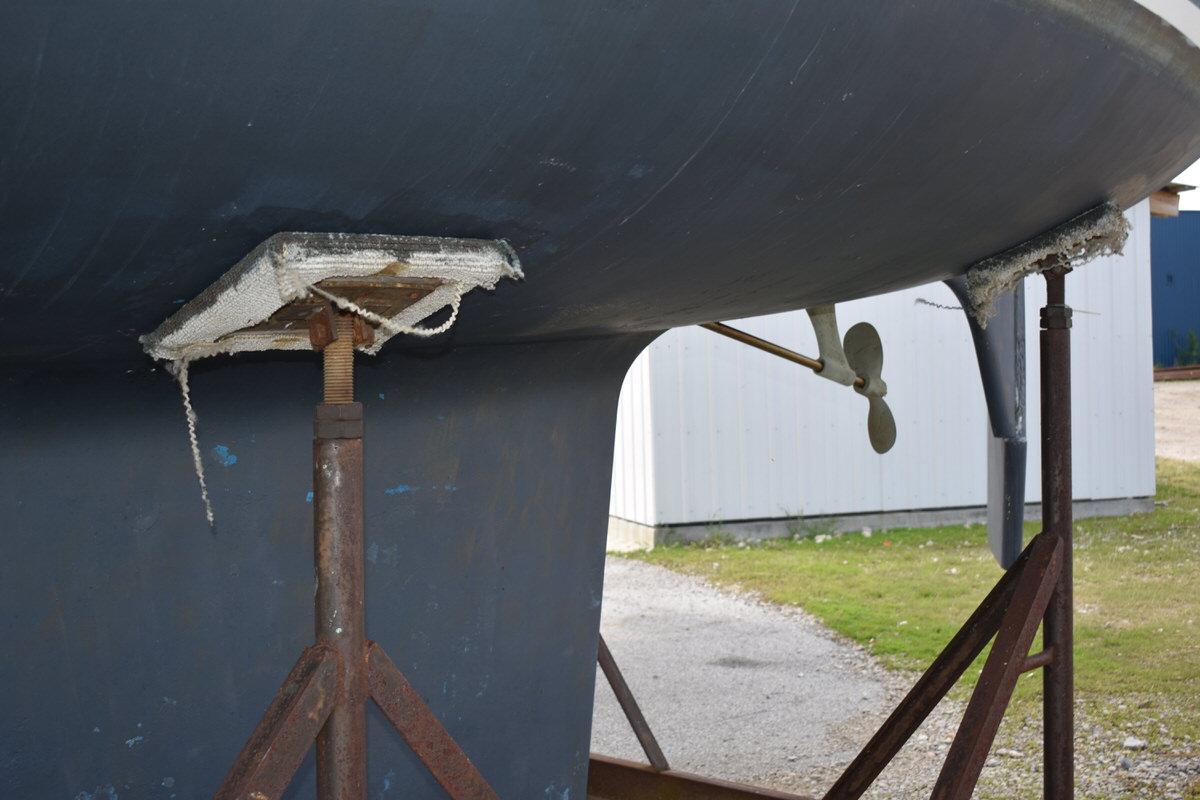 The hull of a blue boat on stands, with a visible propeller.