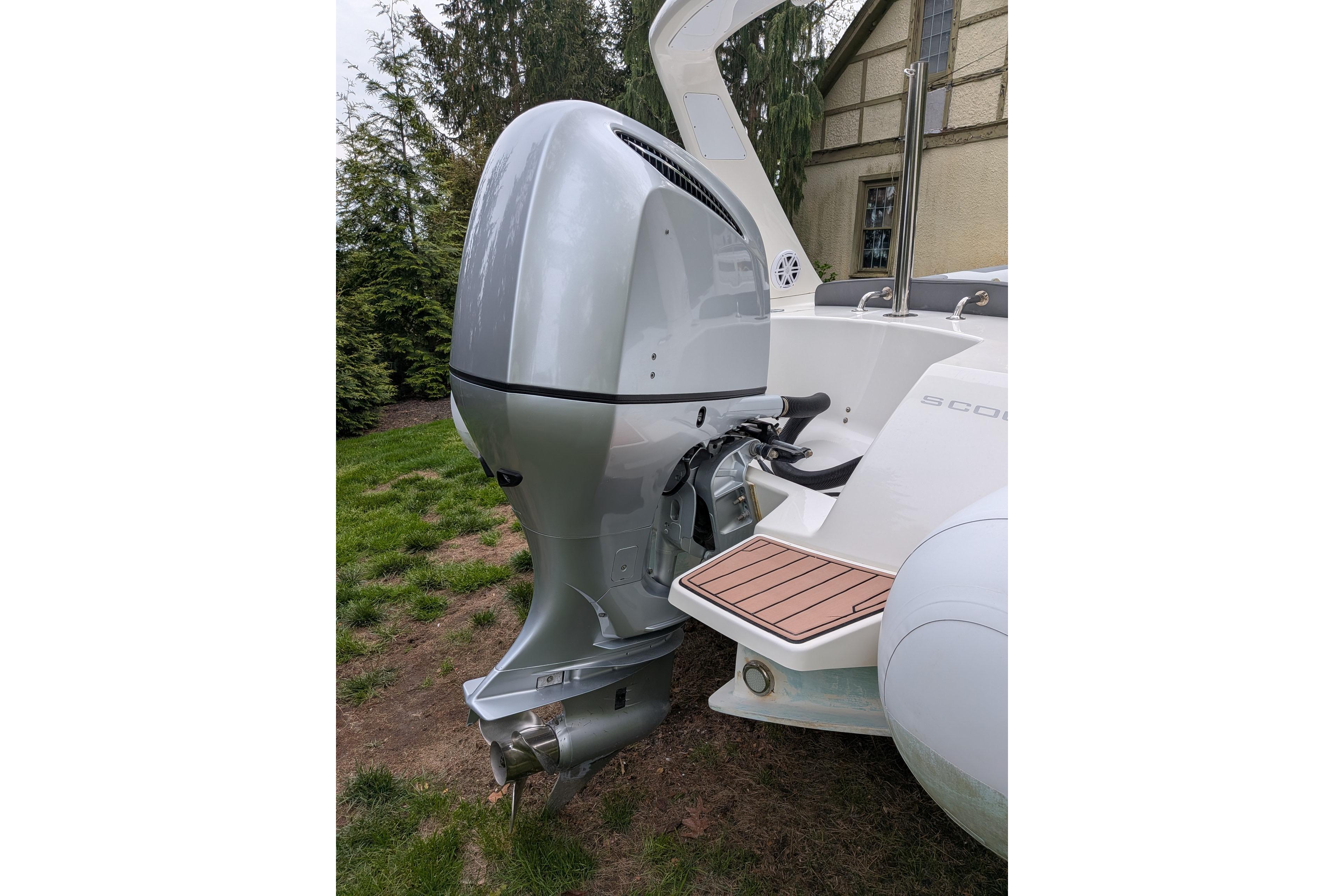 Silver outboard motor on a 2016 Brig E780 boat, parked on grass.
