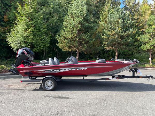2023 Tracker Pro Team 190 TX boat on trailer, parked near lush green trees.