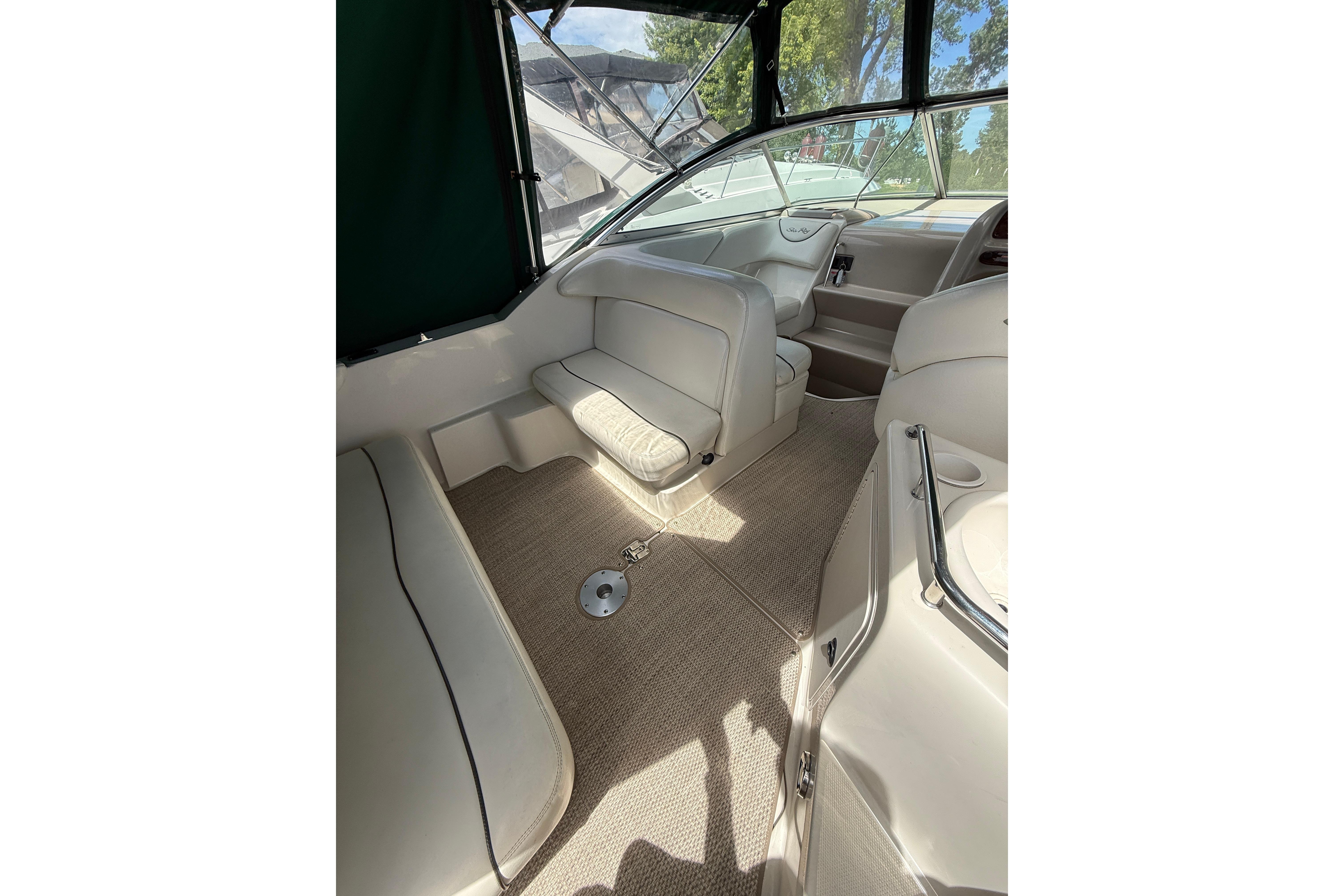 Interior of a 2004 Sea Ray 240 Sundancer boat, featuring beige seating and carpet.