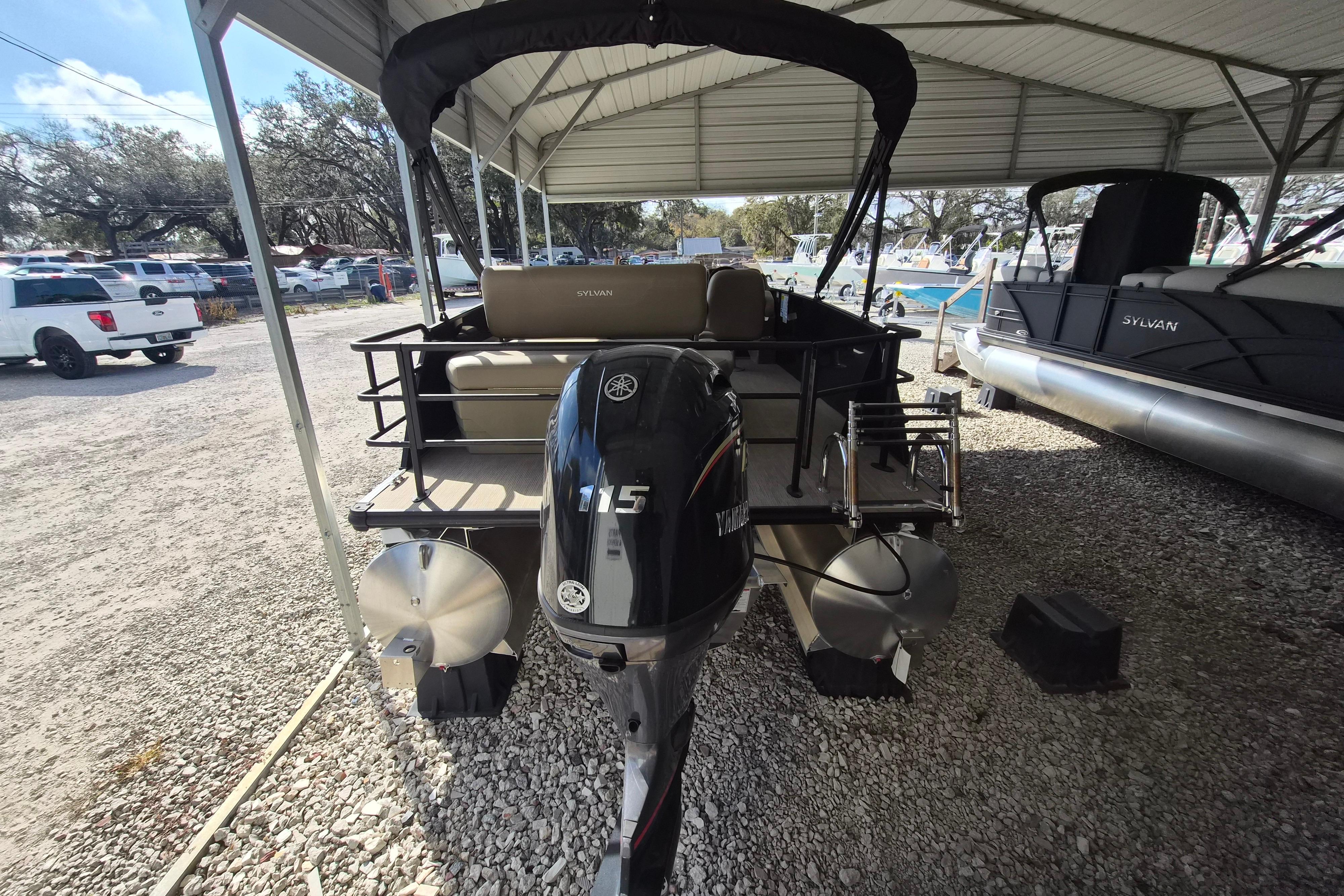 2026 Sylvan Mirage 820 CLZ DH pontoon boat with Yamaha 115 engine, parked under a canopy.