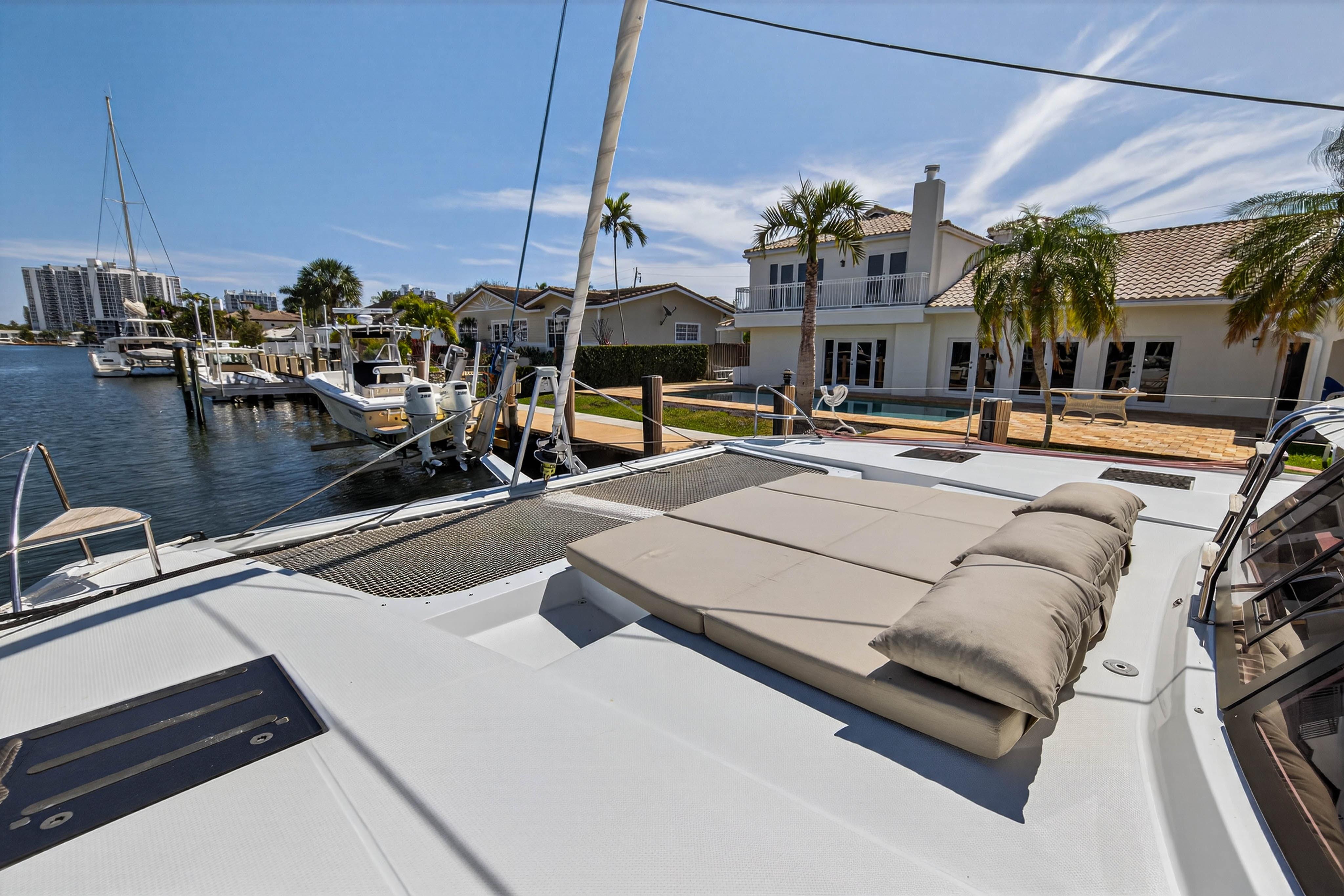 2022 Fountaine Pajot Tanna 47 catamaran docked near waterfront homes, featuring spacious deck.