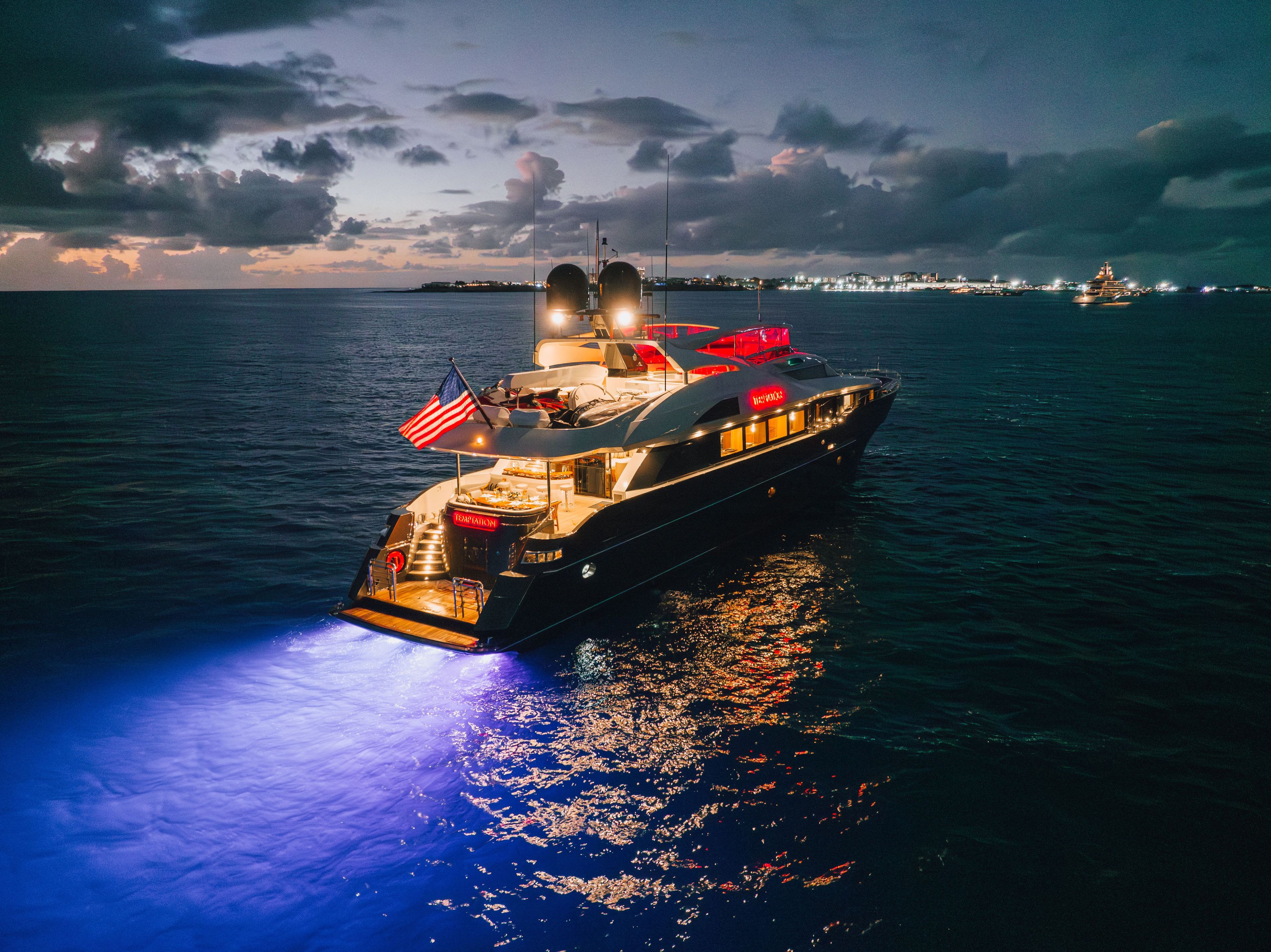 A luxurious 2005 Palmer Johnson yacht, illuminated on calm waters at night.