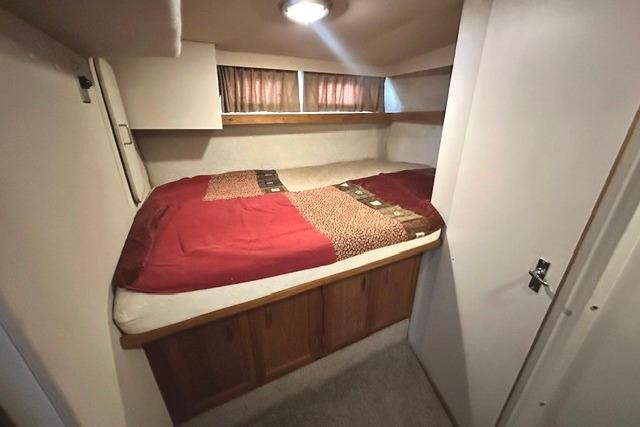 Cozy cabin bedroom in 1989 Carver 32 Aft Cabin Motor Yacht with red bedding.